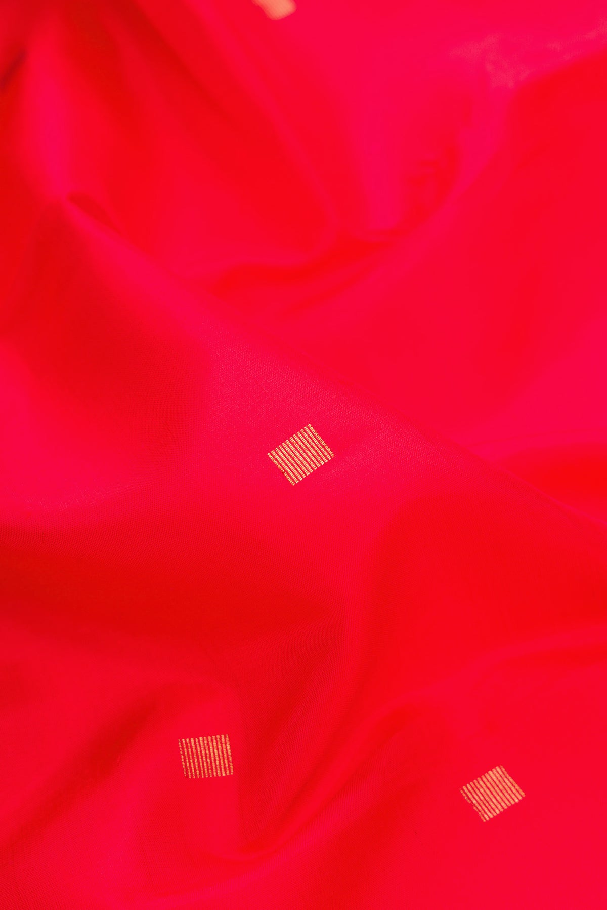 Close up of Red Dual Tone Kanjivaram Silk Saree with Zari Butta on the body and Checks Border.  displaying folds