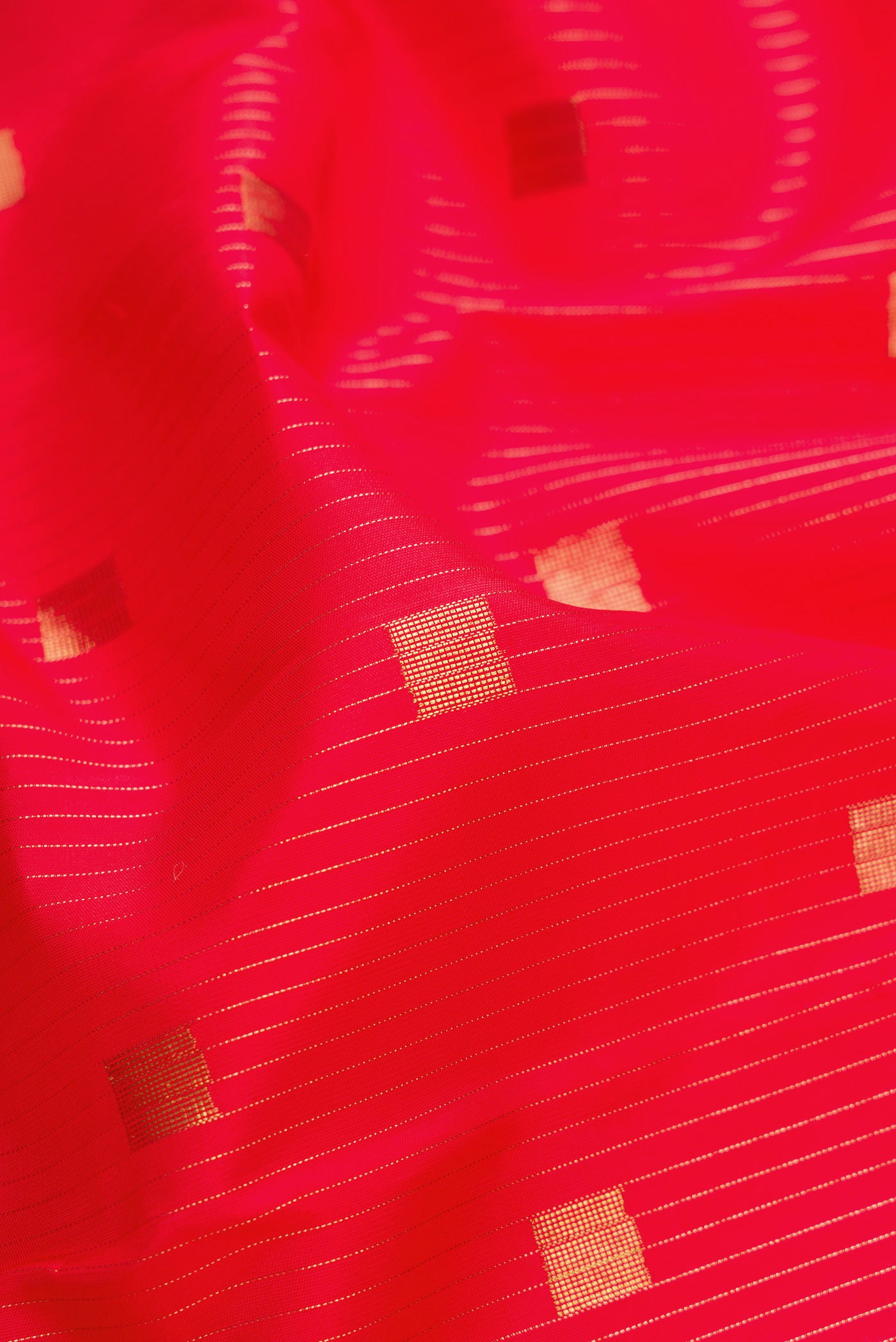 Close up of Pure Silk Pure Zari Red Dual Tone Kanchipuram Saree with Zari Butta on the body and Without Border.  displaying folds