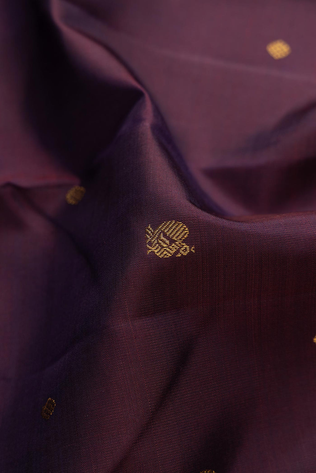 Close up of Pure Silk Pure Zari Burgundy Dual Tone Kanchipuram Saree with Zari Butta on the body and Thin Zari Line displaying folds
