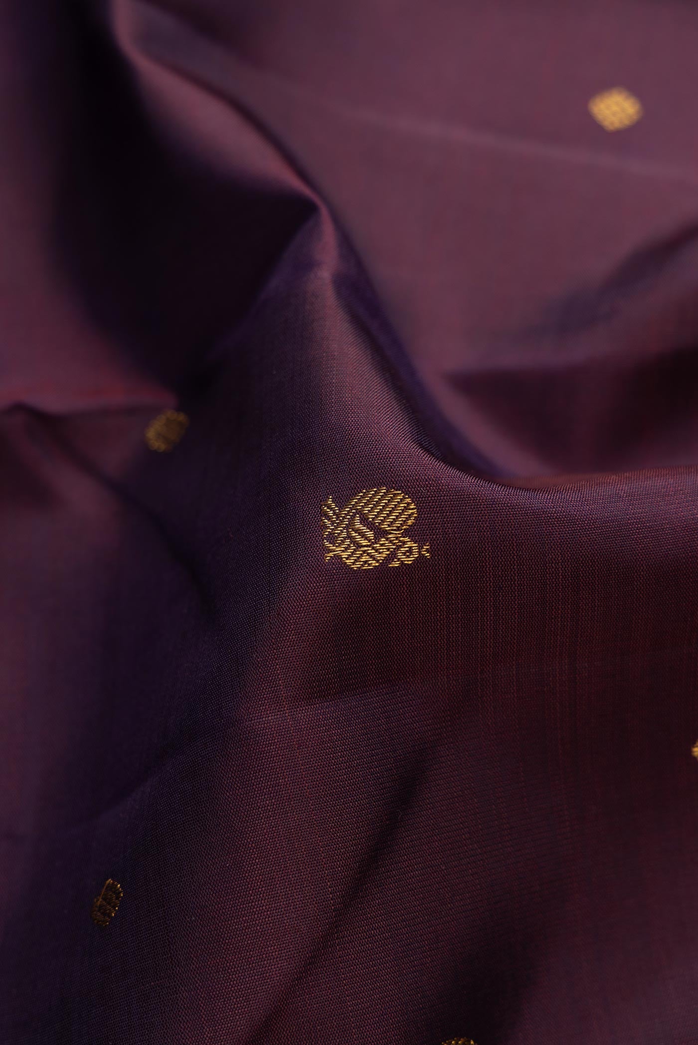 Close up of Pure Silk Pure Zari Burgundy Dual Tone Kanchipuram Saree with Zari Butta on the body and Thin Zari Line displaying folds