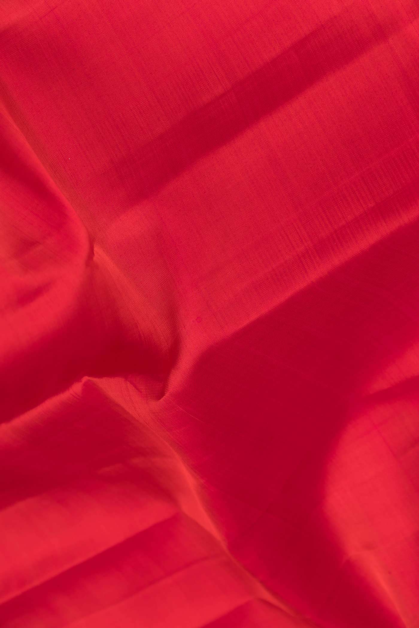 Close up of Red Dual Tone Kanchipuram Saree with Plain Body and Zari Border.  displaying folds