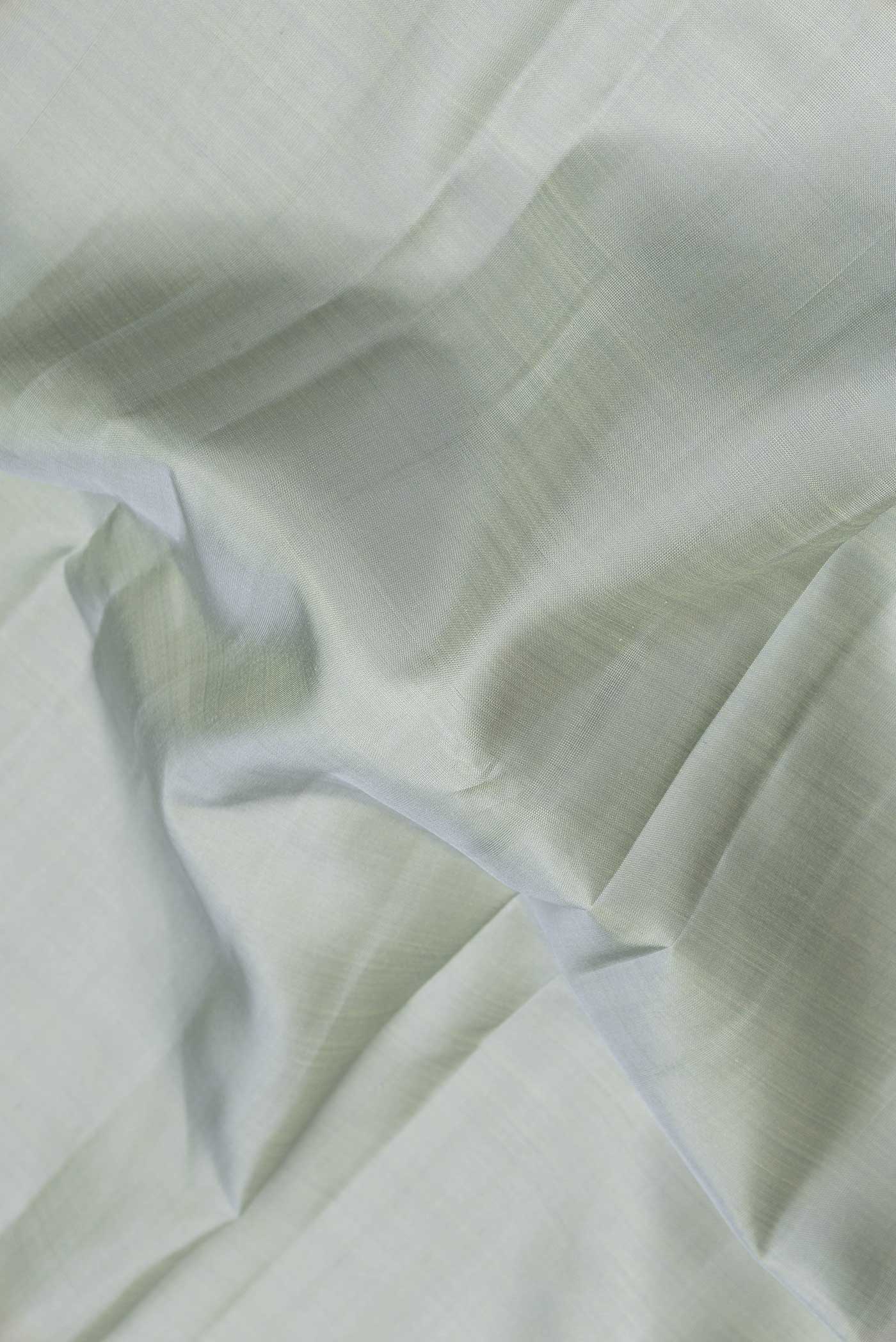 Close up of Grey Dual Tone Kanchipuram Saree with Plain Body and Zari Border.  displaying folds