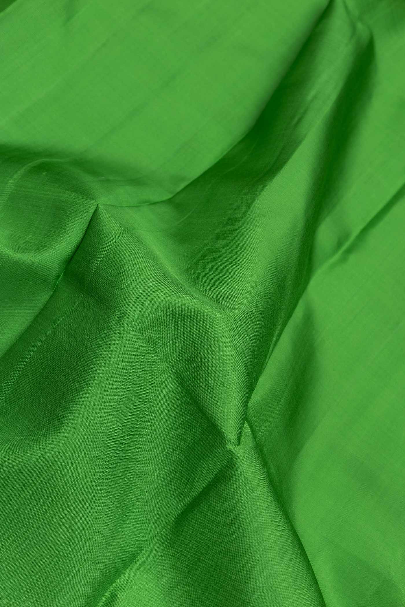 Close up of Parrot Green Dual Tone Kanchipuram Saree with Plain Body and Zari Border.  displaying folds