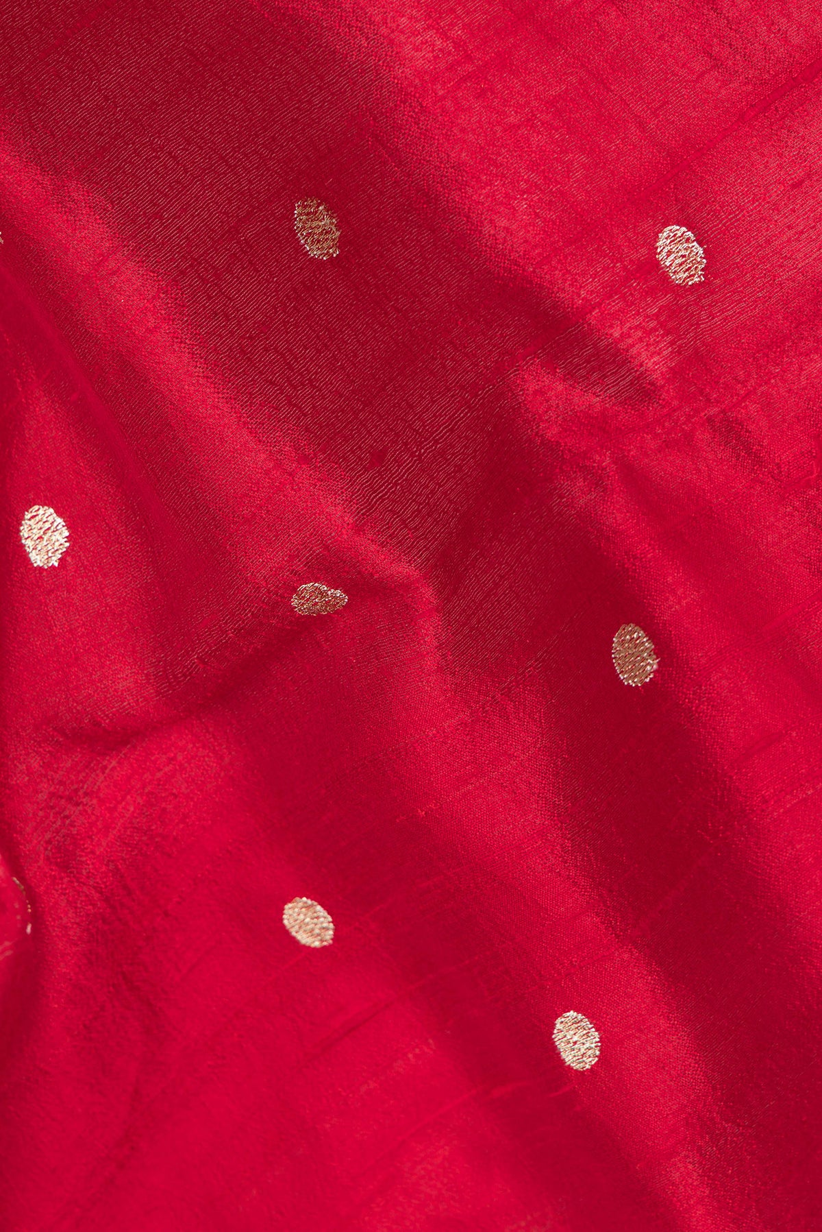 Close up of Pure Silk Red Tussar Saree with Zari Butta on the body and Embroidery Border.  displaying folds