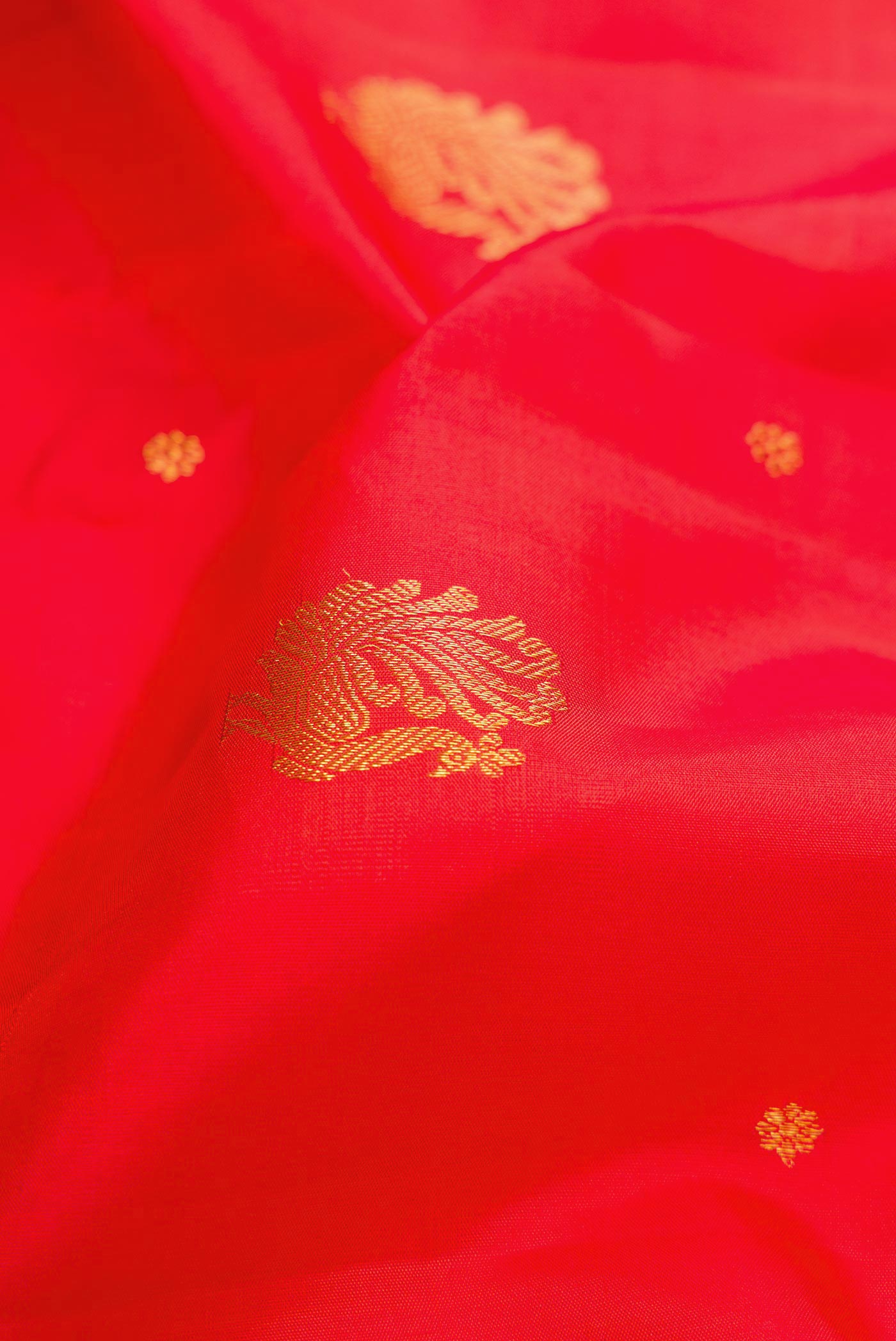 Close up of Orange Dual Tone Kanjivaram Silk Saree with Zari Butta on the body and Zari Border.  displaying folds