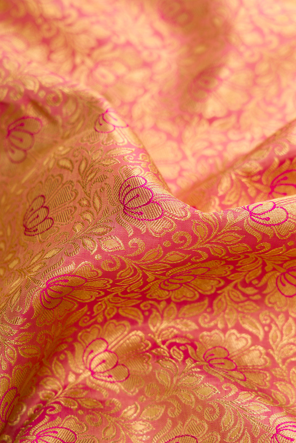 Close up of Pure Silk Pure Zari Rose Gold Dual Tone Kanjivaram Saree with Zari Brocade on the body and Zari Border.  displaying folds