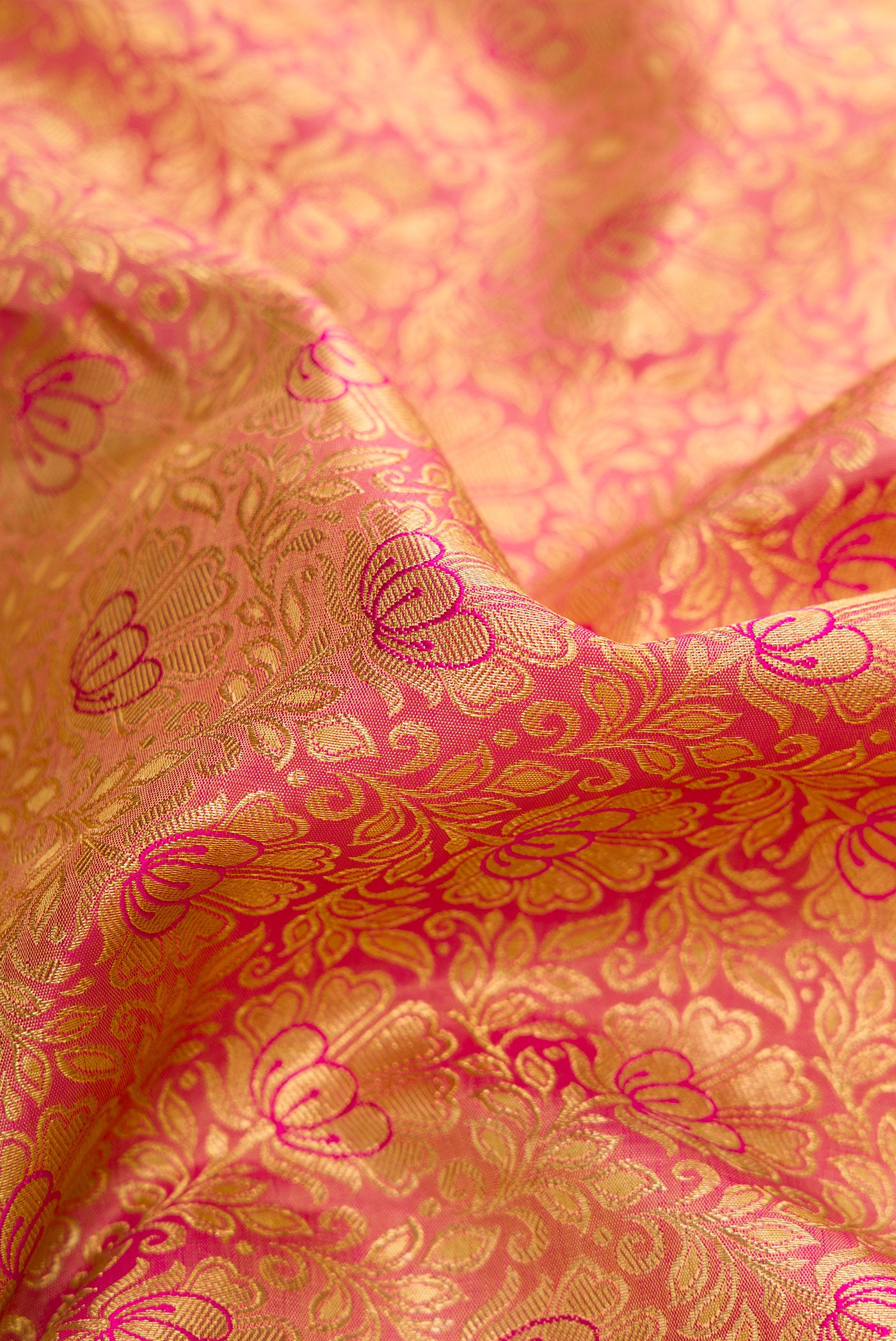 Close up of Pure Silk Pure Zari Rose Gold Dual Tone Kanjivaram Saree with Zari Brocade on the body and Zari Border.  displaying folds