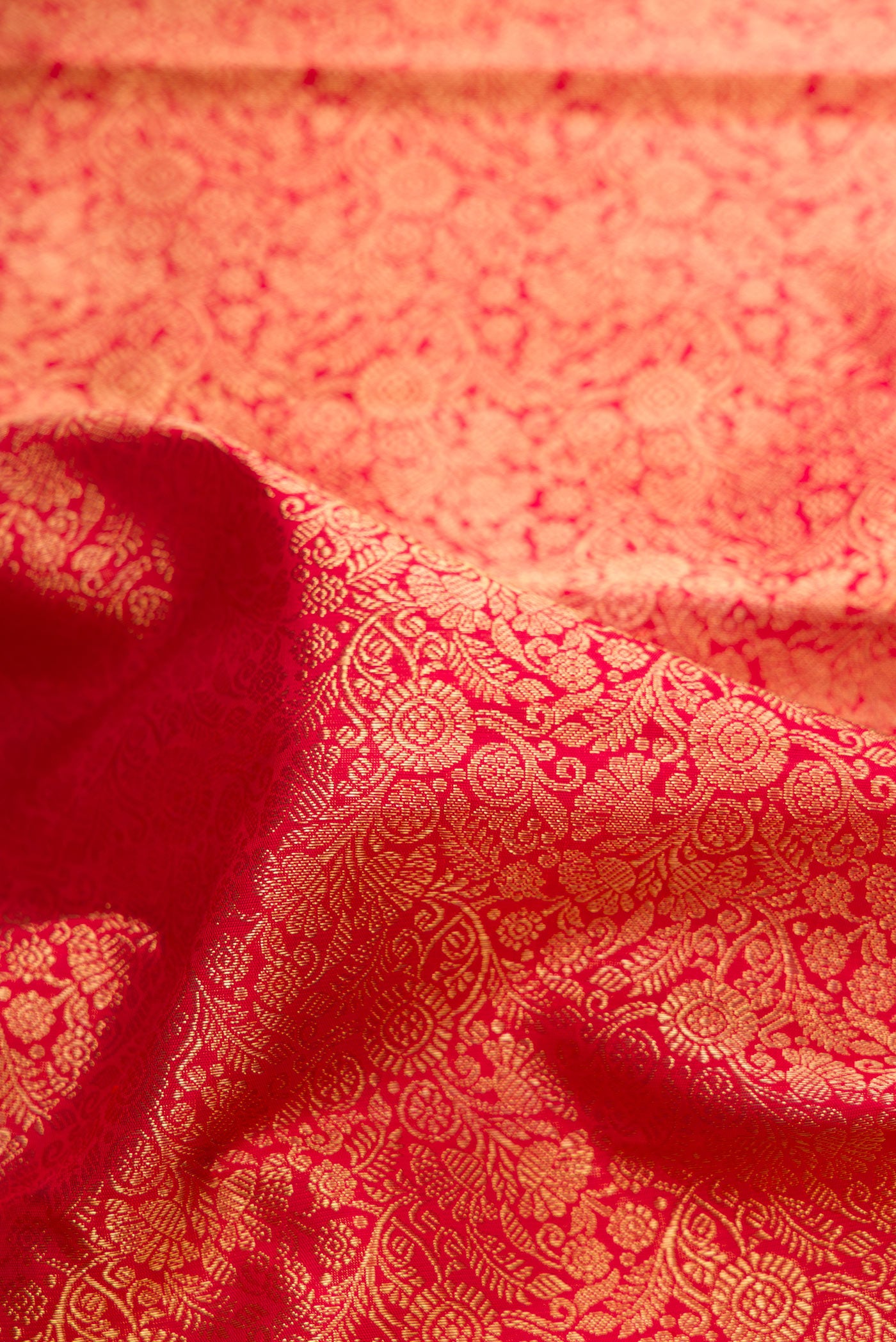Close up of Pure Silk Pure Zari Red Dual Tone Kanjivaram Saree with Zari Brocade on the body and Zari Border.  displaying folds