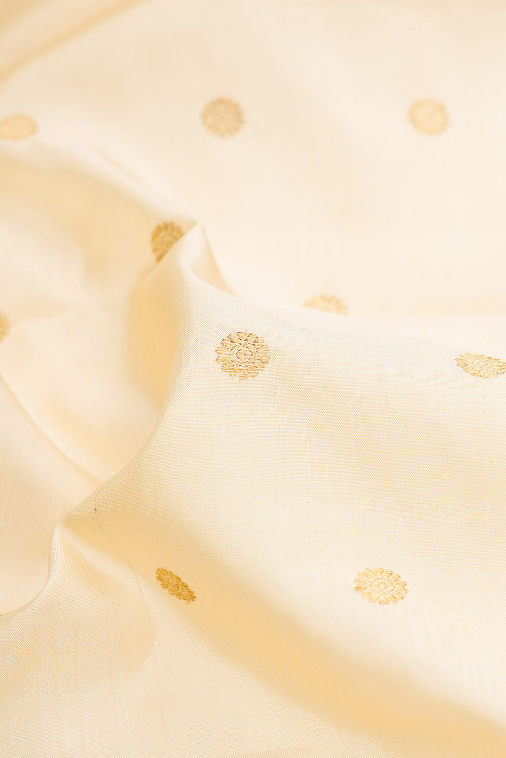Close up of Pure Silk Pure Zari Off White Dual Tone Kanjivaram Saree with Zari Butta on the body and Fancy Border.  displaying folds