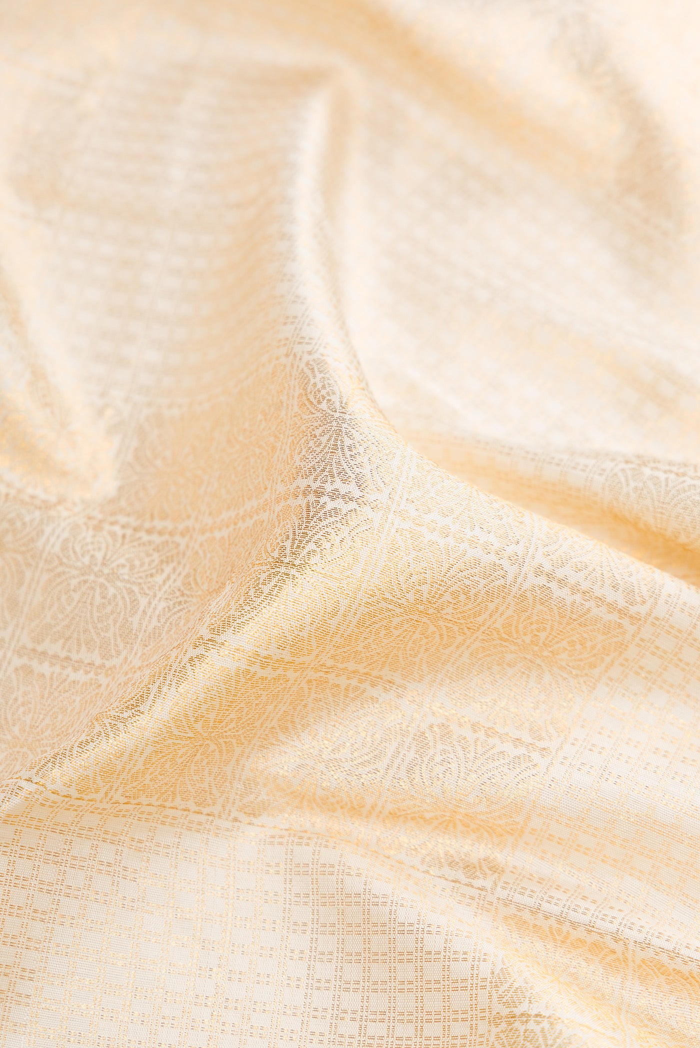 Close up of Off White Dual Tone Kanchipuram Silk Saree with Zari Brocade on the body and Zari Border.  displaying folds