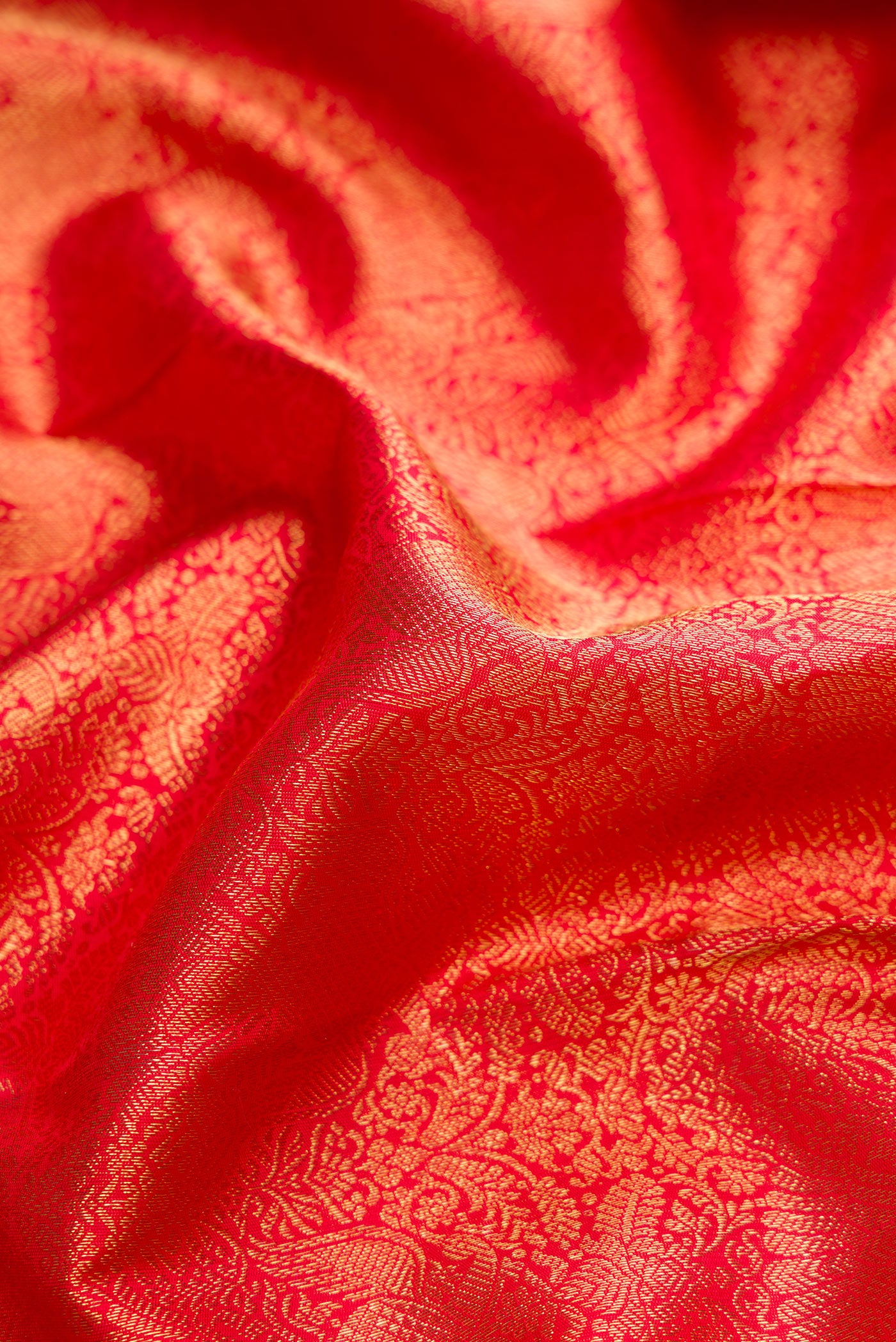 Close up of Pure Silk Pure Zari Red Dual Tone Kanjivaram Saree with Zari Brocade on the body and Zari Border.  displaying folds