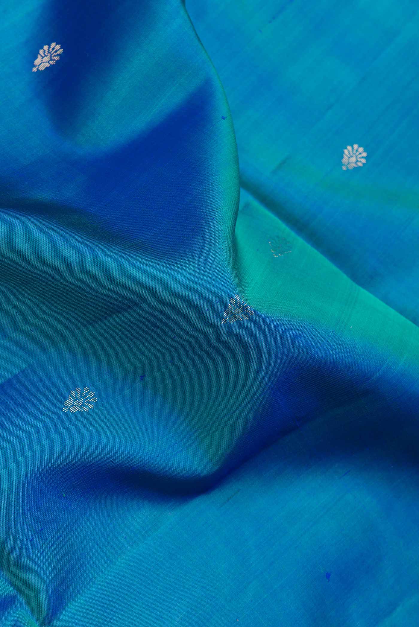 Close up of Peacock Blue Dual Tone Soft Silk Saree with Zari Butta on the body and Fancy Border.  displaying folds