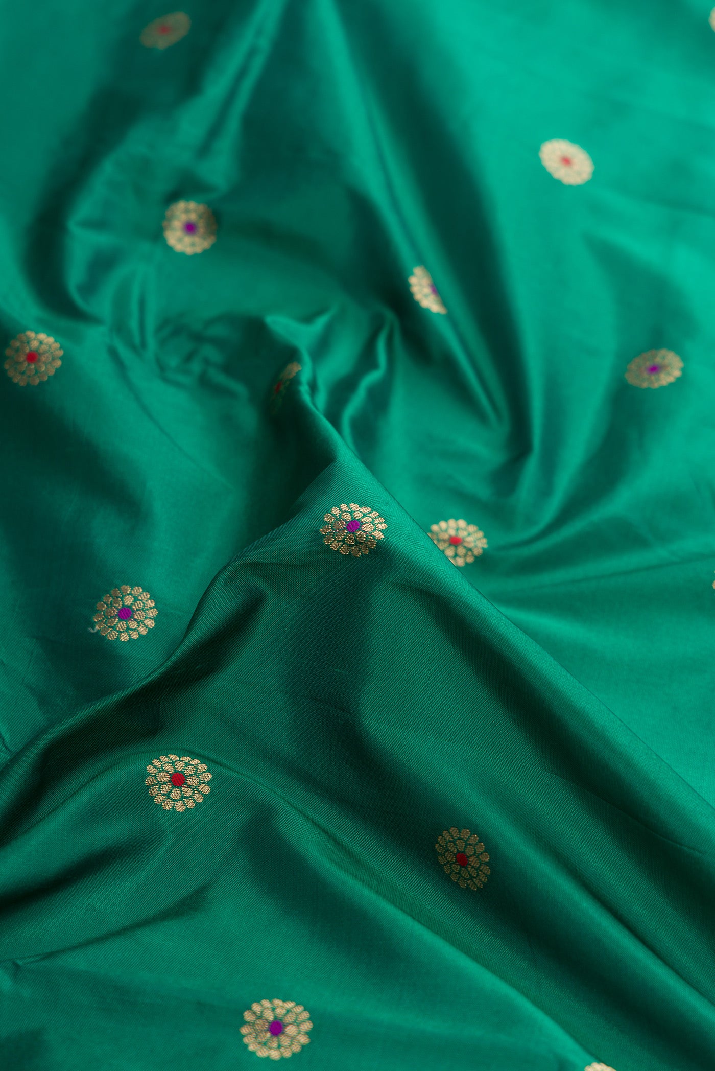 Close up of Green Dual Tone Paithani Silk Saree with Zari And Thread Butta on the body and Zari Border.  displaying folds