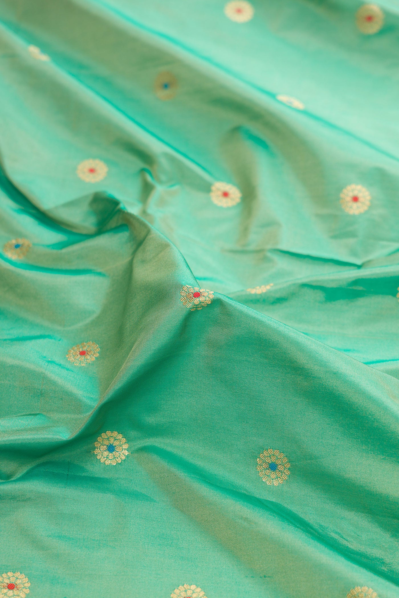 Close up of Light Green Dual Tone Paithani Silk Saree with Zari And Thread Butta on the body and Zari Border.  displaying folds
