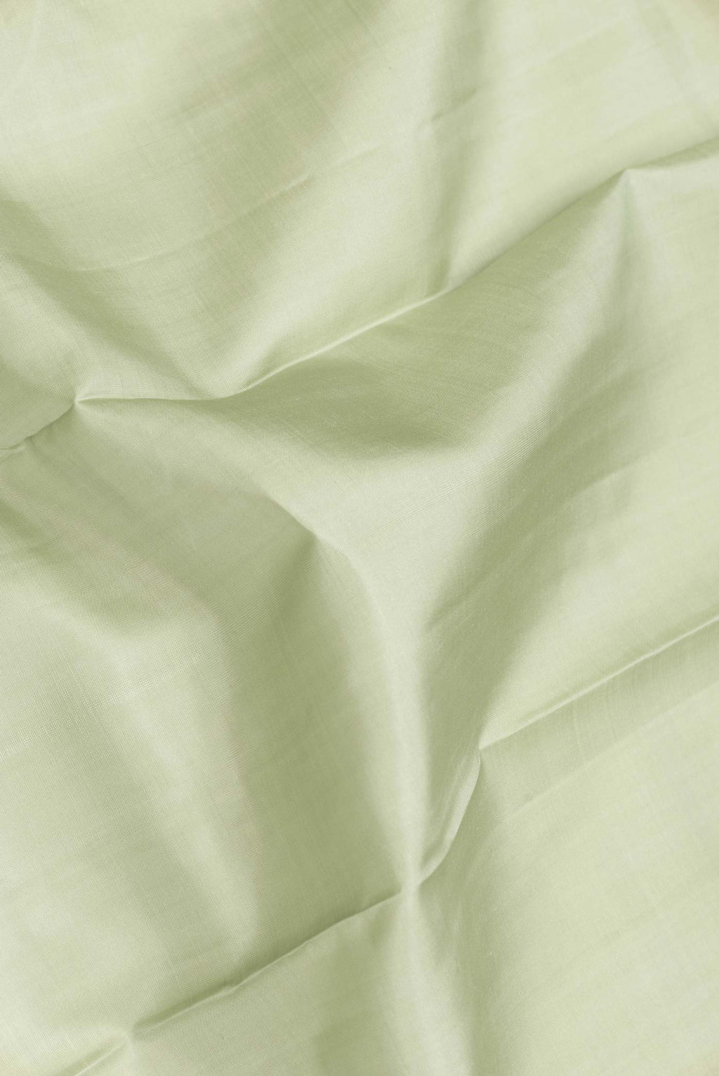 Close up of Pista Green Dual Tone Kanchipuram Saree with Plain Body and Zari Border.  displaying folds