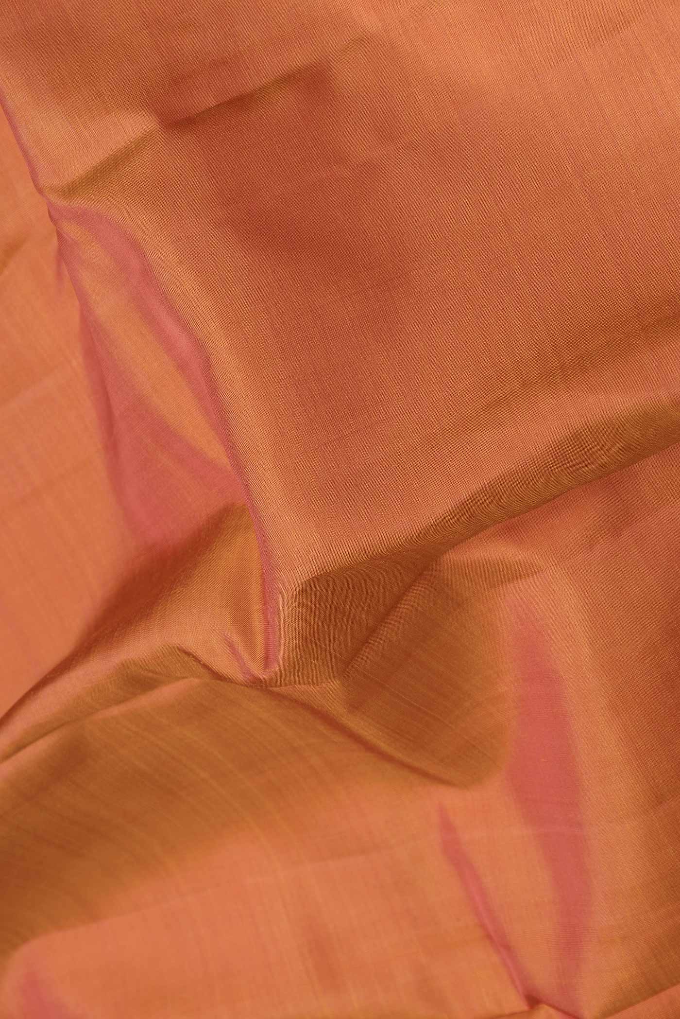 Close up of Golden Peach Dual Tone Kanchipuram Saree with Plain Body and Zari Border.  displaying folds