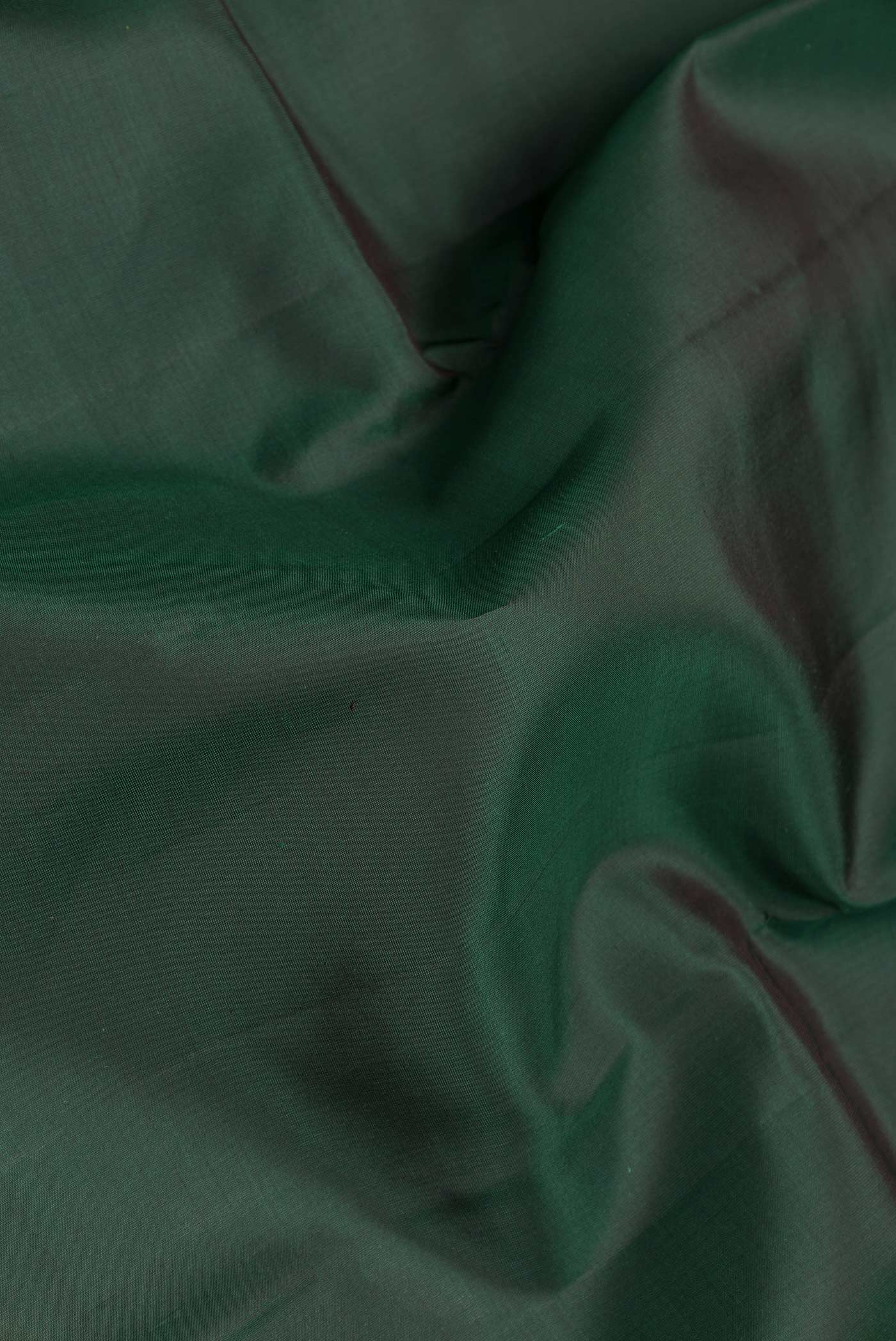 Close up of Bottle Green Dual Tone Kanchipuram Saree with Plain Body and Zari Border.  displaying folds
