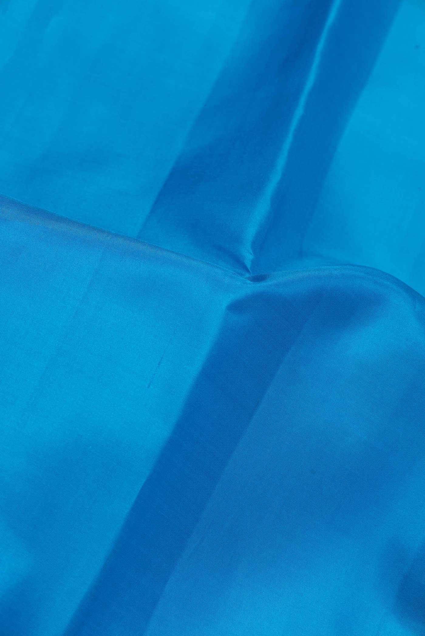 Close up of Peacock Blue Dual Tone Kanchipuram Saree with Plain Body and Zari Border.  displaying folds