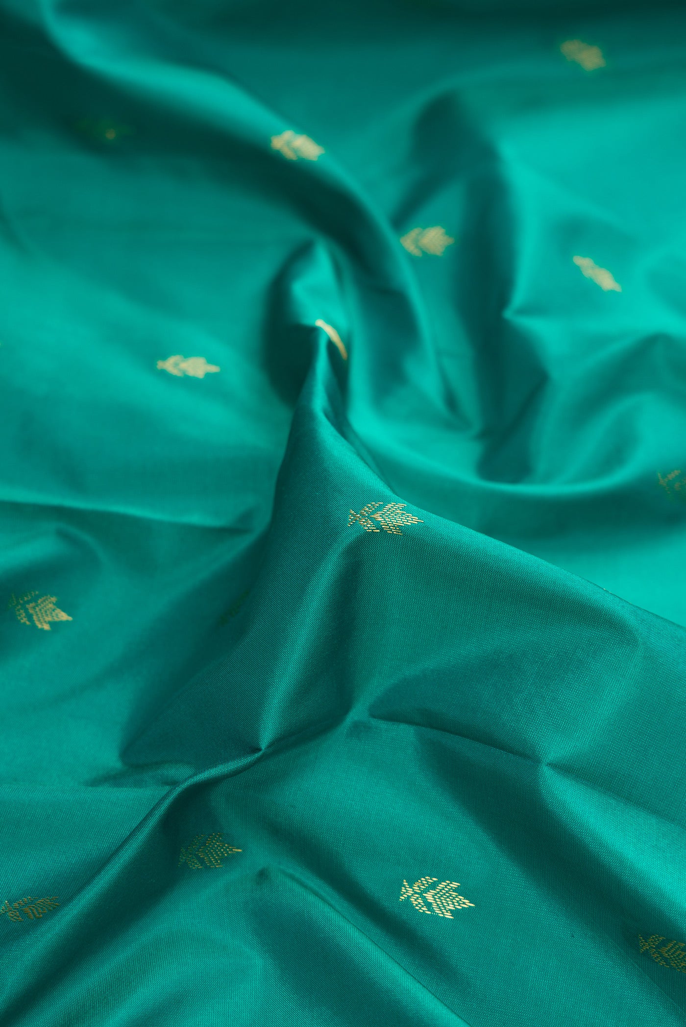 Close up of Green Dual Tone Kanchipuram Silk Saree with Zari Butta on the body and Zari Border.  displaying folds