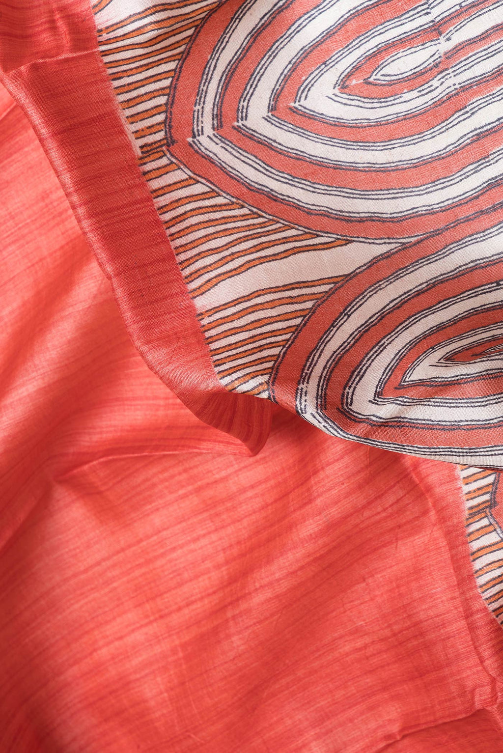 Close up of Red Dual Tone Tussar Silk Saree with Printed design on the body and Zari Border.  displaying folds