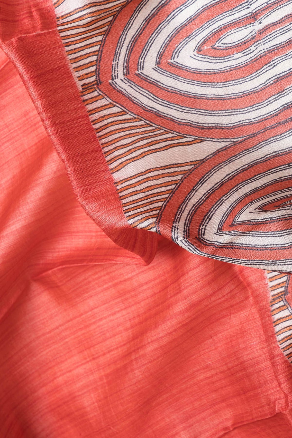 Close up of Red Dual Tone Tussar Silk Saree with Printed design on the body and Zari Border.  displaying folds