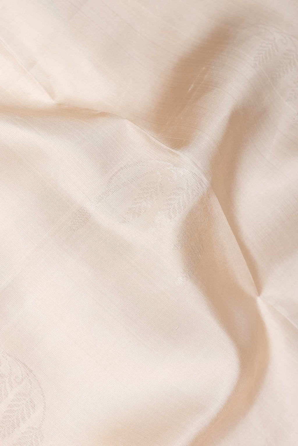 Close up of Beige Dual Tone Soft Silk Saree with Zari Butta on the body and Zari Border.  displaying folds