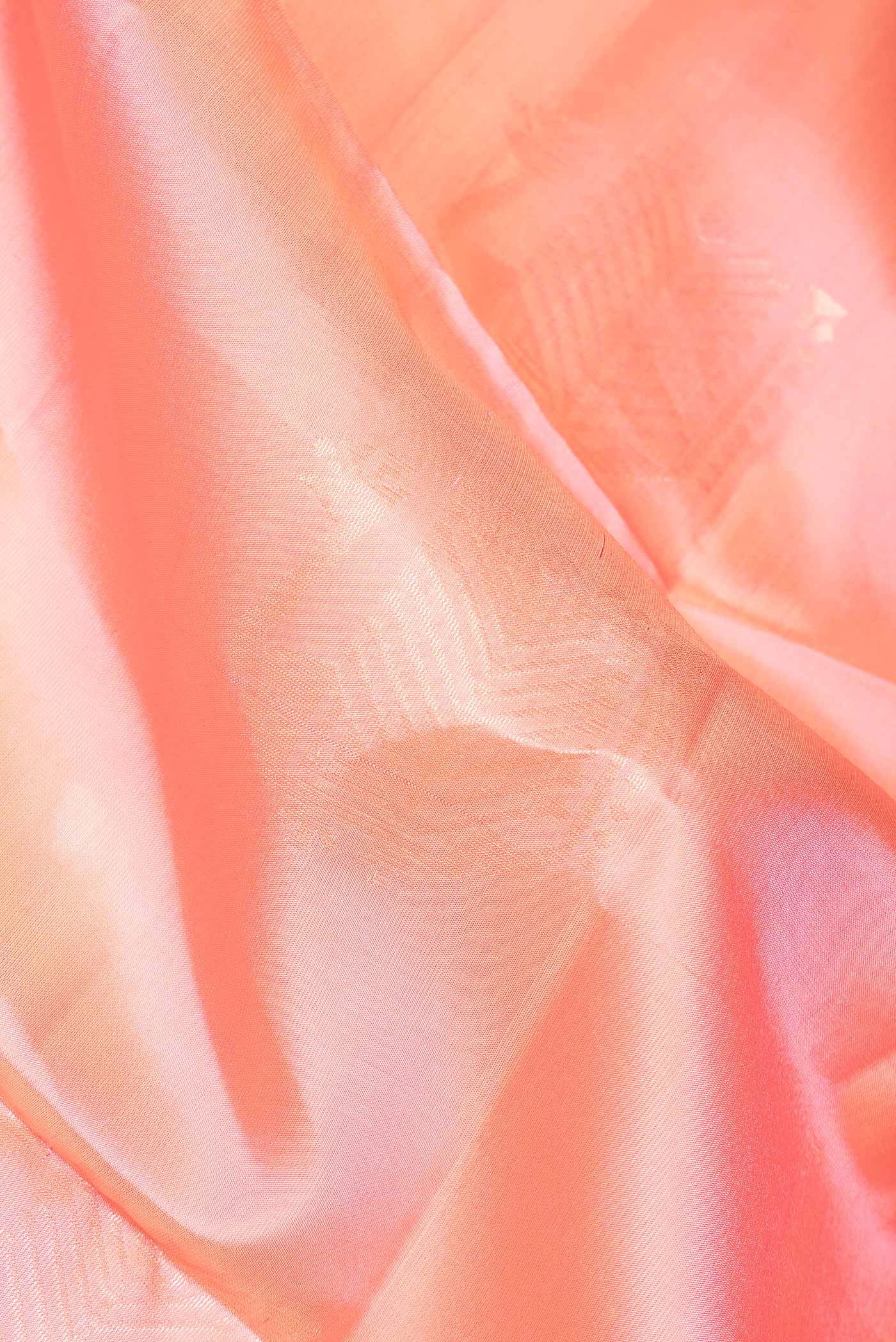 Close up of Peach Dual Tone Soft Silk Saree with Zari Butta on the body and Zari Border.  displaying folds
