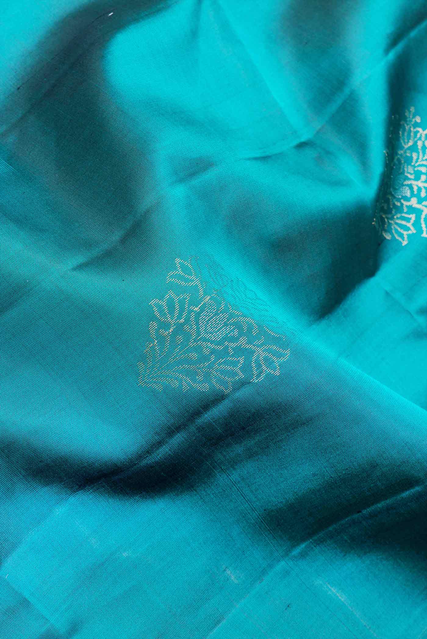 Close up of Peacock Blue Dual Tone Soft Silk Saree with Zari Butta on the body and Fancy Border.  displaying folds
