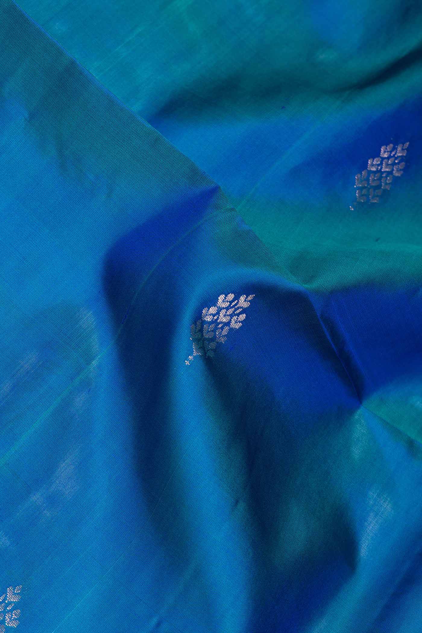 Close up of Peacock Blue Dual Tone Soft Silk Saree with Zari Butta on the body and Zari Border.  displaying folds