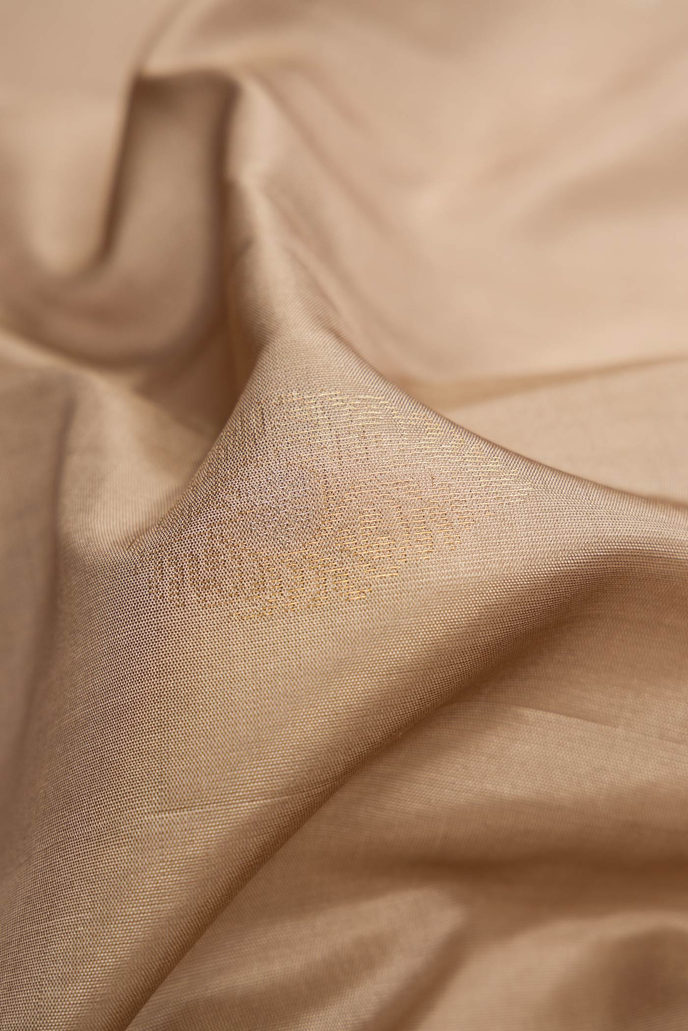 Close up of Beige Dual Tone Soft Silk Saree with Zari Butta on the body and Zari Border.  displaying folds
