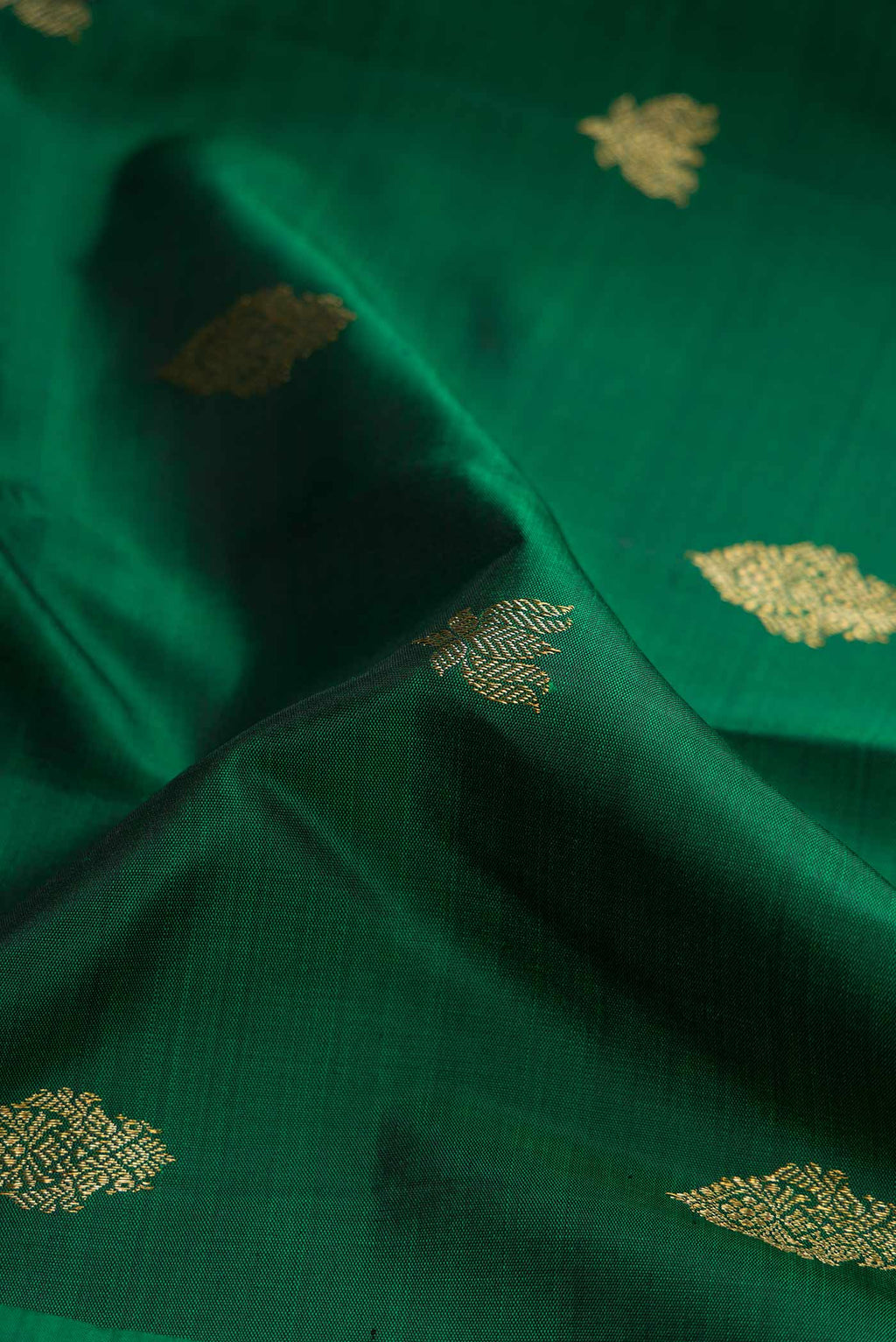 Close up of Pure Silk Pure Zari Bottle Green Dual Tone Kanchipuram Saree with Zari Butta on the body and Zari Border displaying folds