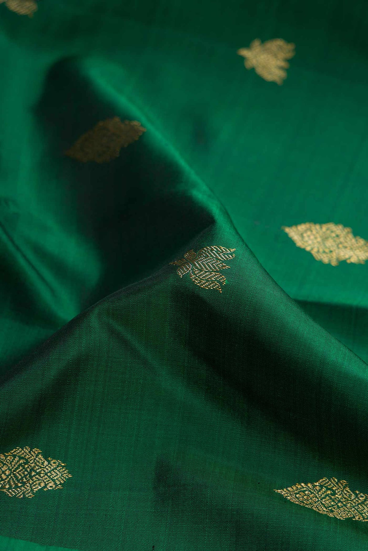 Close up of Pure Silk Pure Zari Bottle Green Dual Tone Kanchipuram Saree with Zari Butta on the body and Zari Border displaying folds