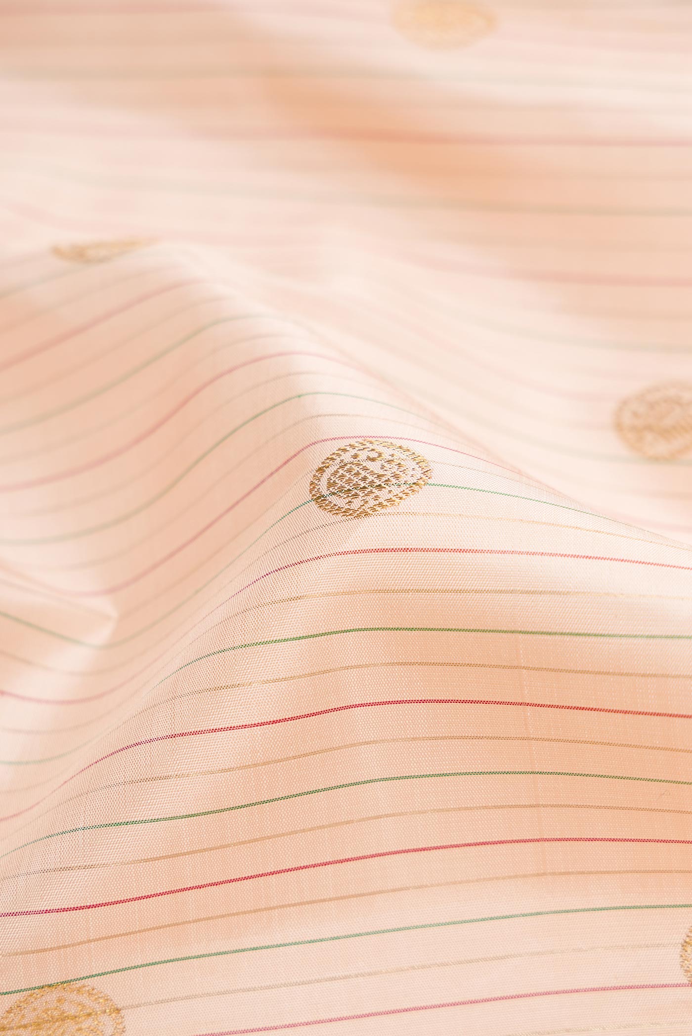 Close up of Pure Silk Pure Zari Rose Gold Dual Tone Kanchipuram Saree with Stripes on the body and Zari Border displaying folds