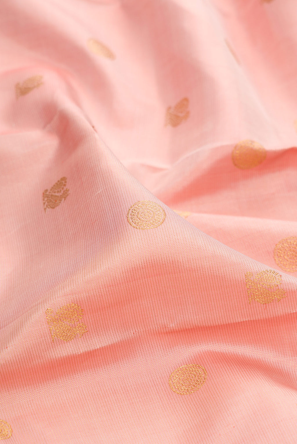 Close up of Peach Kanchipuram Silk Saree with Zari Butta on the body and Zari And Thread Border.  displaying folds