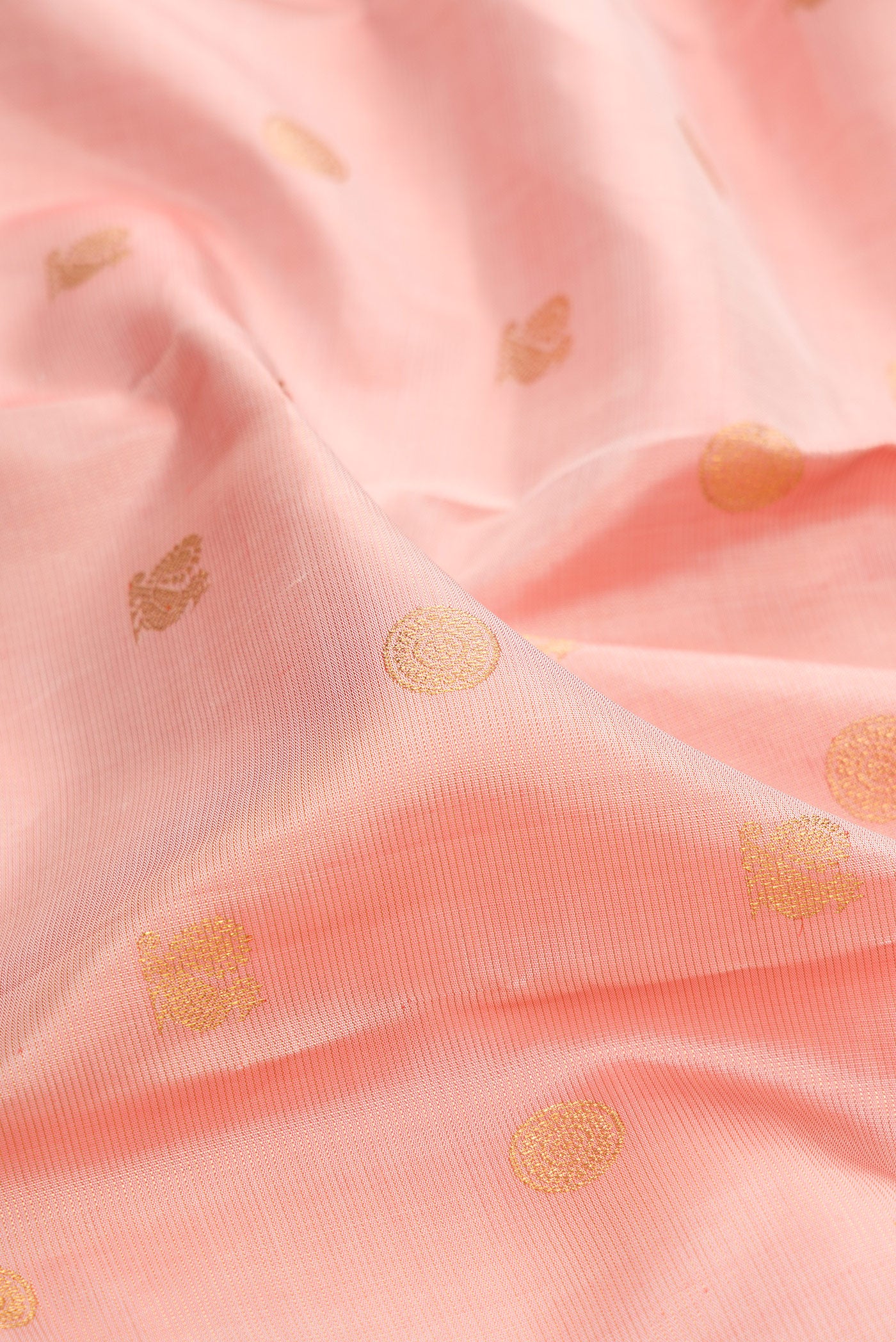 Close up of Peach Kanchipuram Silk Saree with Zari Butta on the body and Zari And Thread Border.  displaying folds