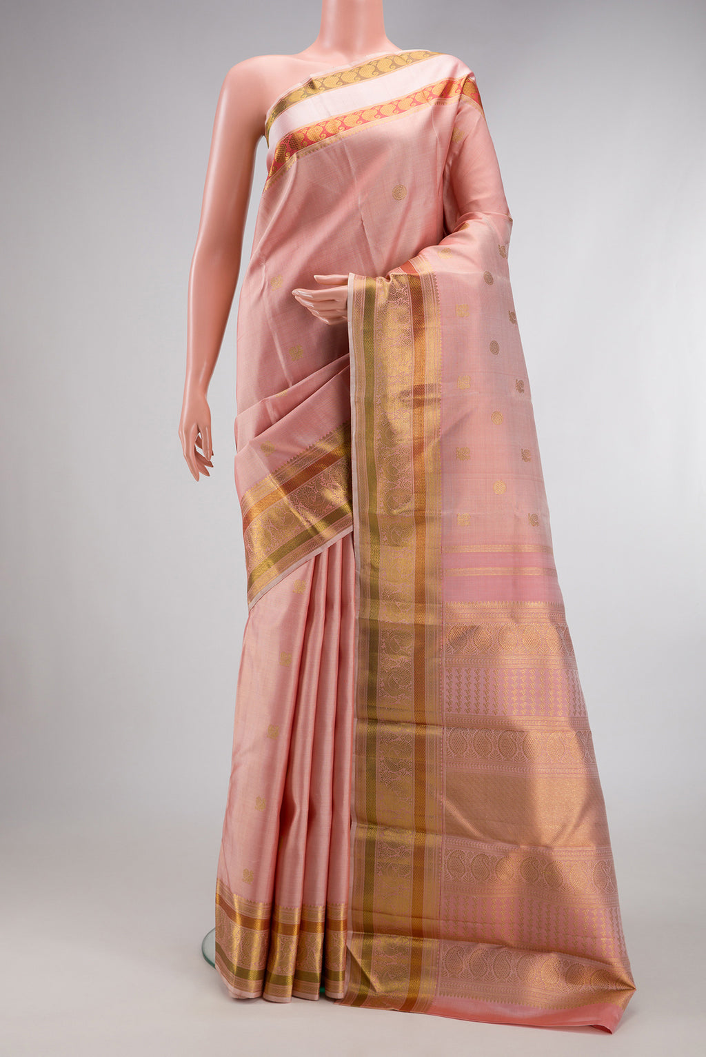 Peach Kanchipuram Silk Saree with Zari Butta on the body and Zari And Thread Border.  displayed on a mannequin