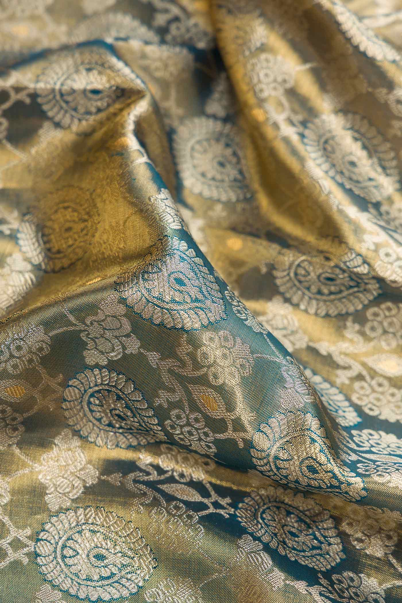 Close up of Mehandi Green Dual Tone Kanjivaram Tissue Silk Saree with Zari Brocade on the body and Zari Border.  displaying folds