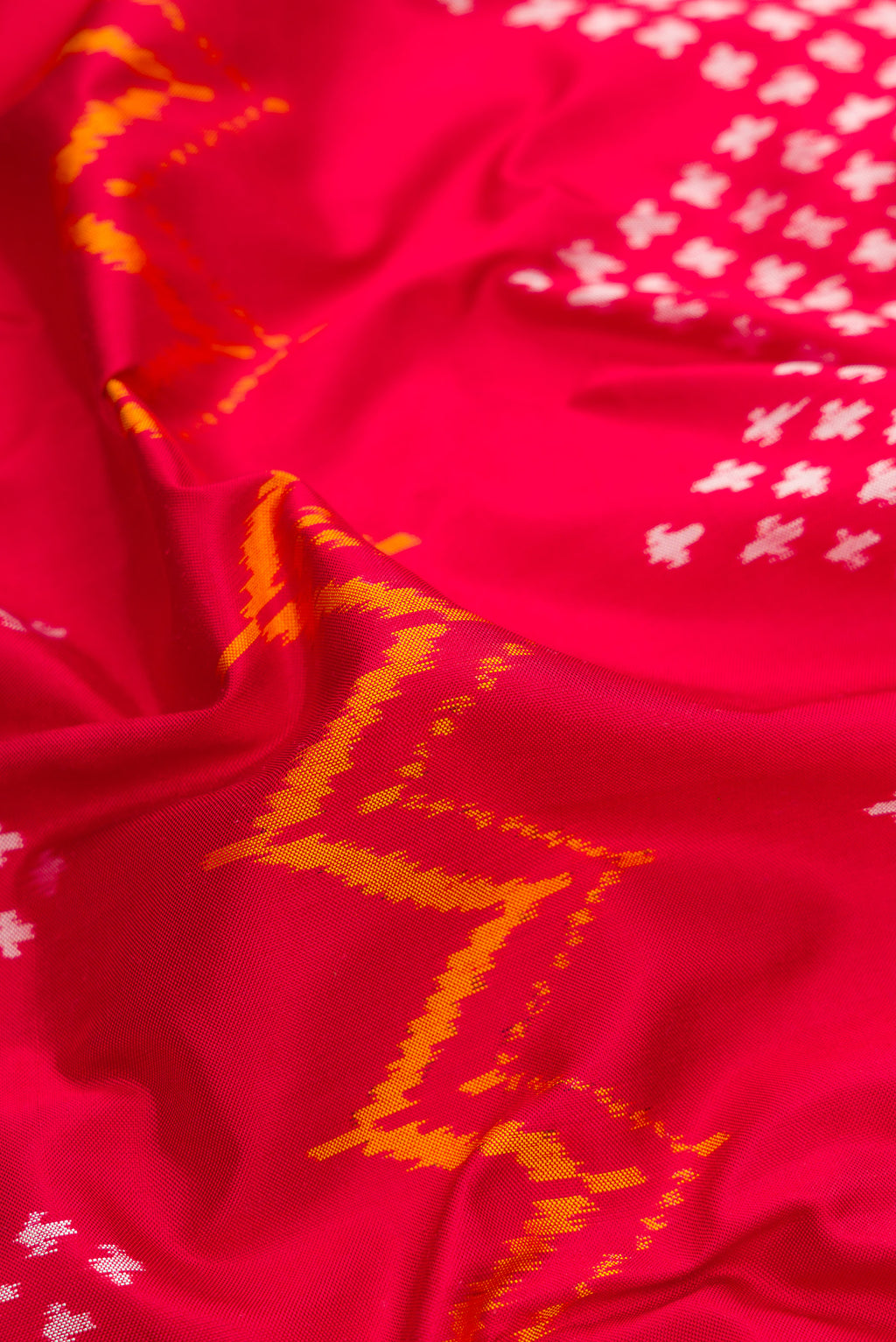 Close up of Red Dual Tone Double Ikat Saree with Ikat Print on the body and Ikat Border.  displaying folds