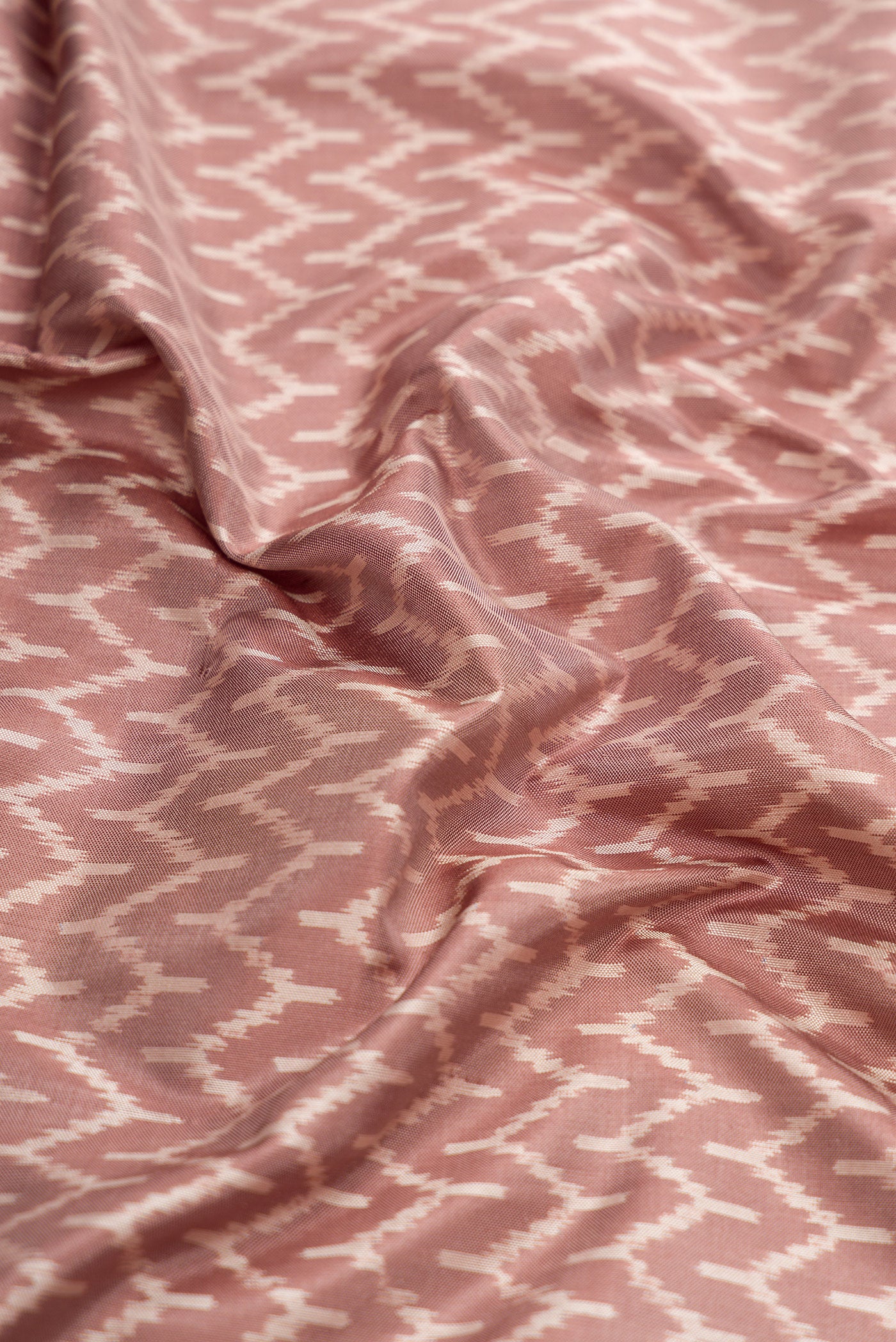 Close up of Brown Dual Tone Double Ikat Saree with Ikat Print on the body and Zari Border.  displaying folds