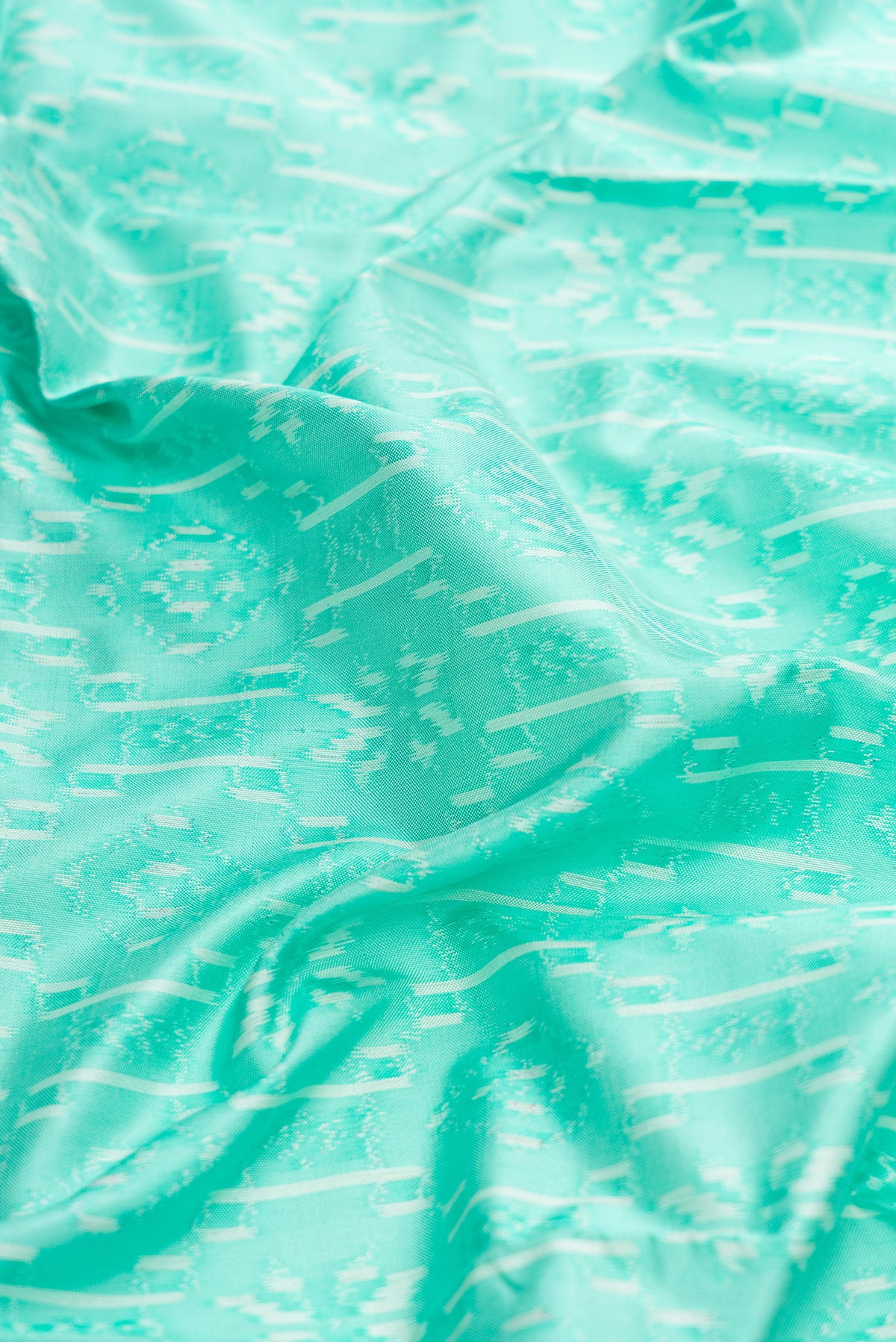 Close up of Sea Green Dual Tone Double Ikat Saree with Ikat Print on the body and Zari Border.  displaying folds
