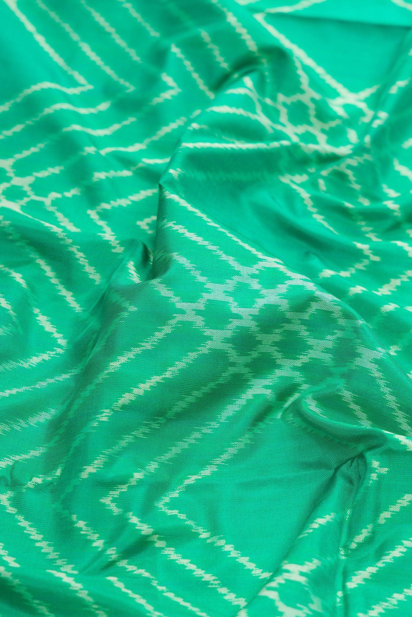 Close up of Sea Green Dual Tone Double Ikat Saree with Ikat Print on the body and Zari Border.  displaying folds