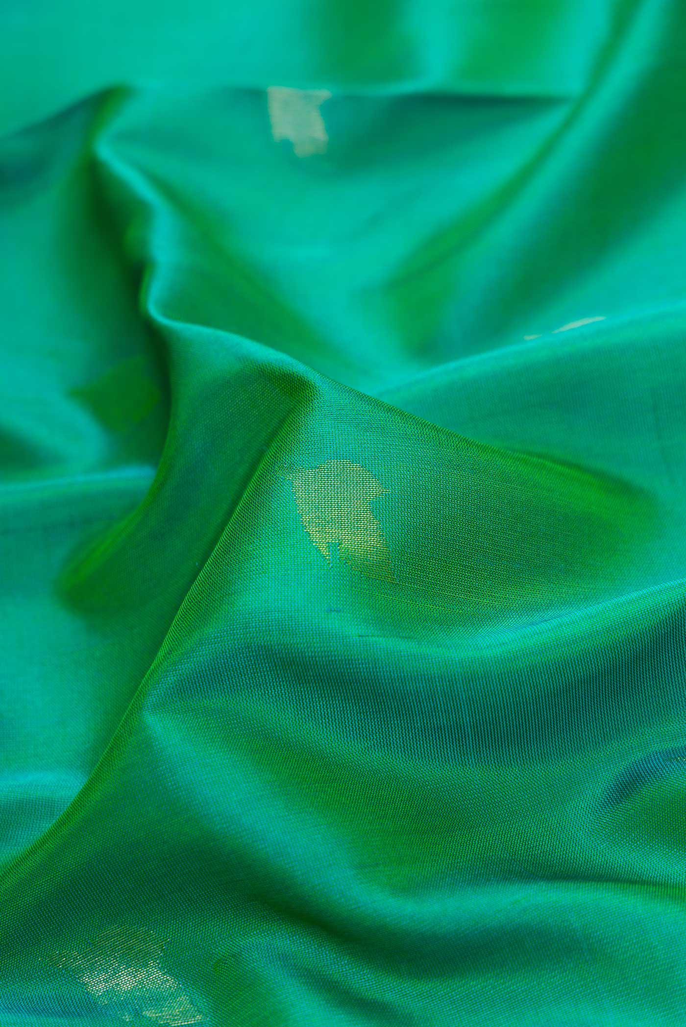 Close up of Green Dual Tone Uppada Silk Saree with Zari Butta on the body and Zari Border.  displaying folds