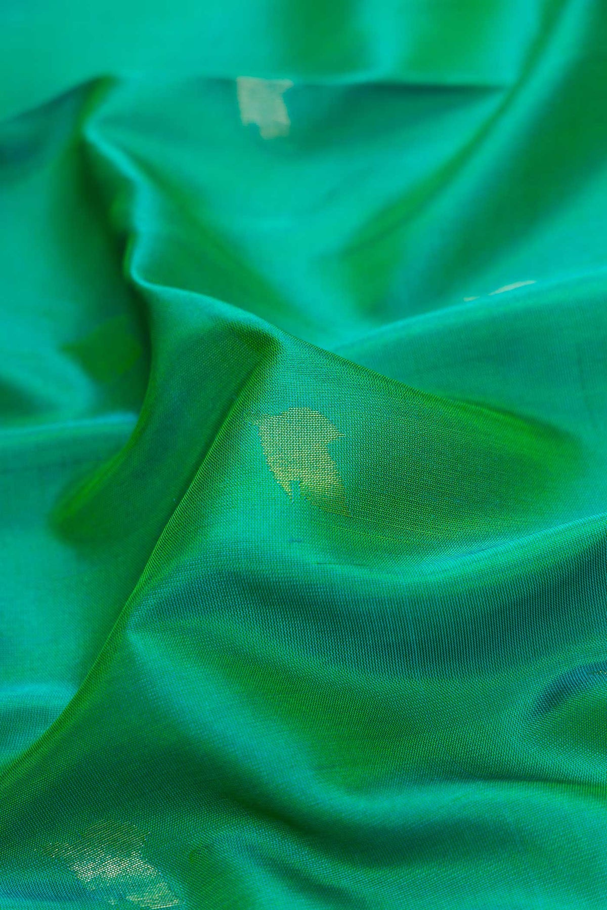 Close up of Green Dual Tone Uppada Silk Saree with Zari Butta on the body and Zari Border.  displaying folds