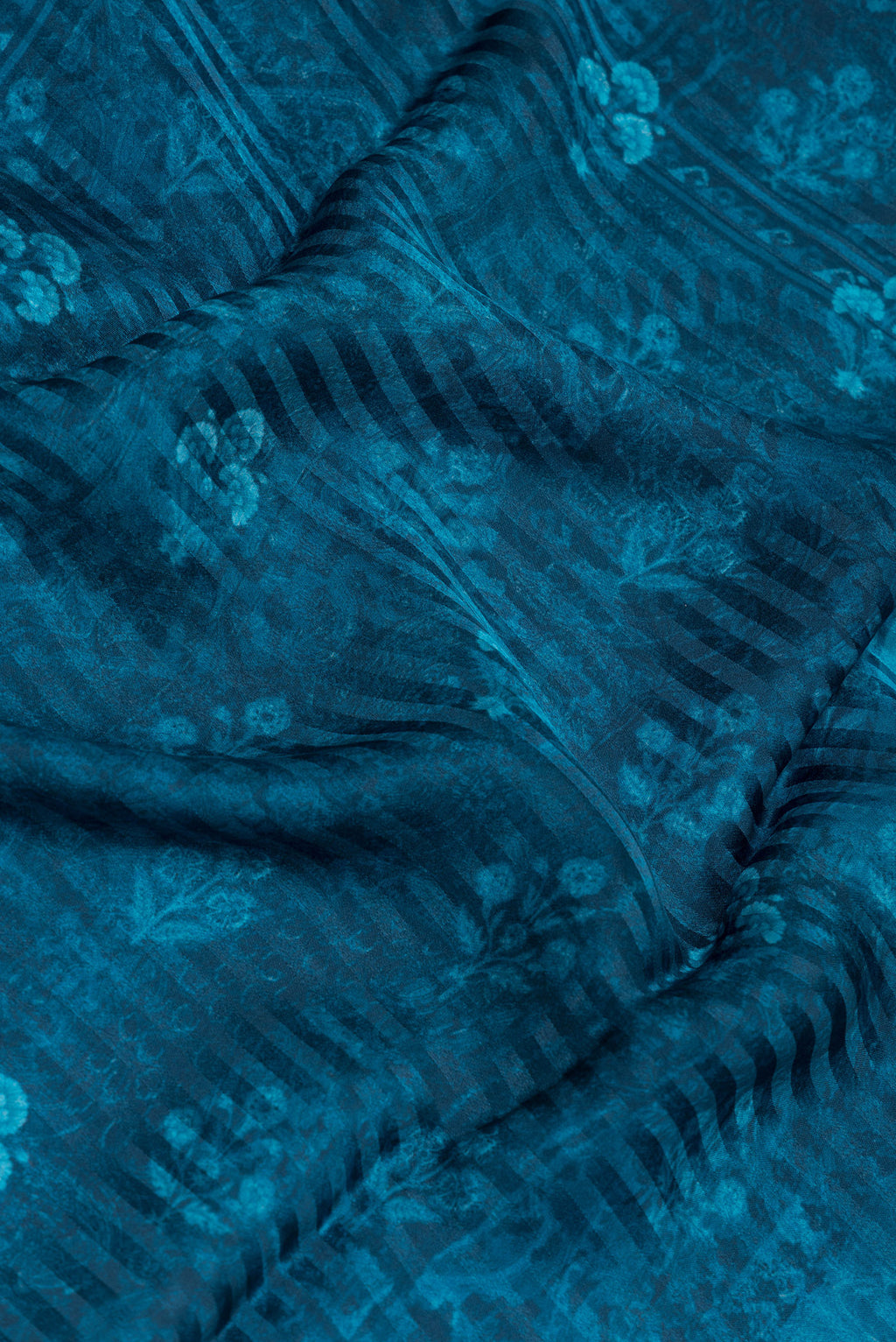 Close up of Peacock Blue Crepe Saree with Printed design on the body and Printed Border.  displaying folds