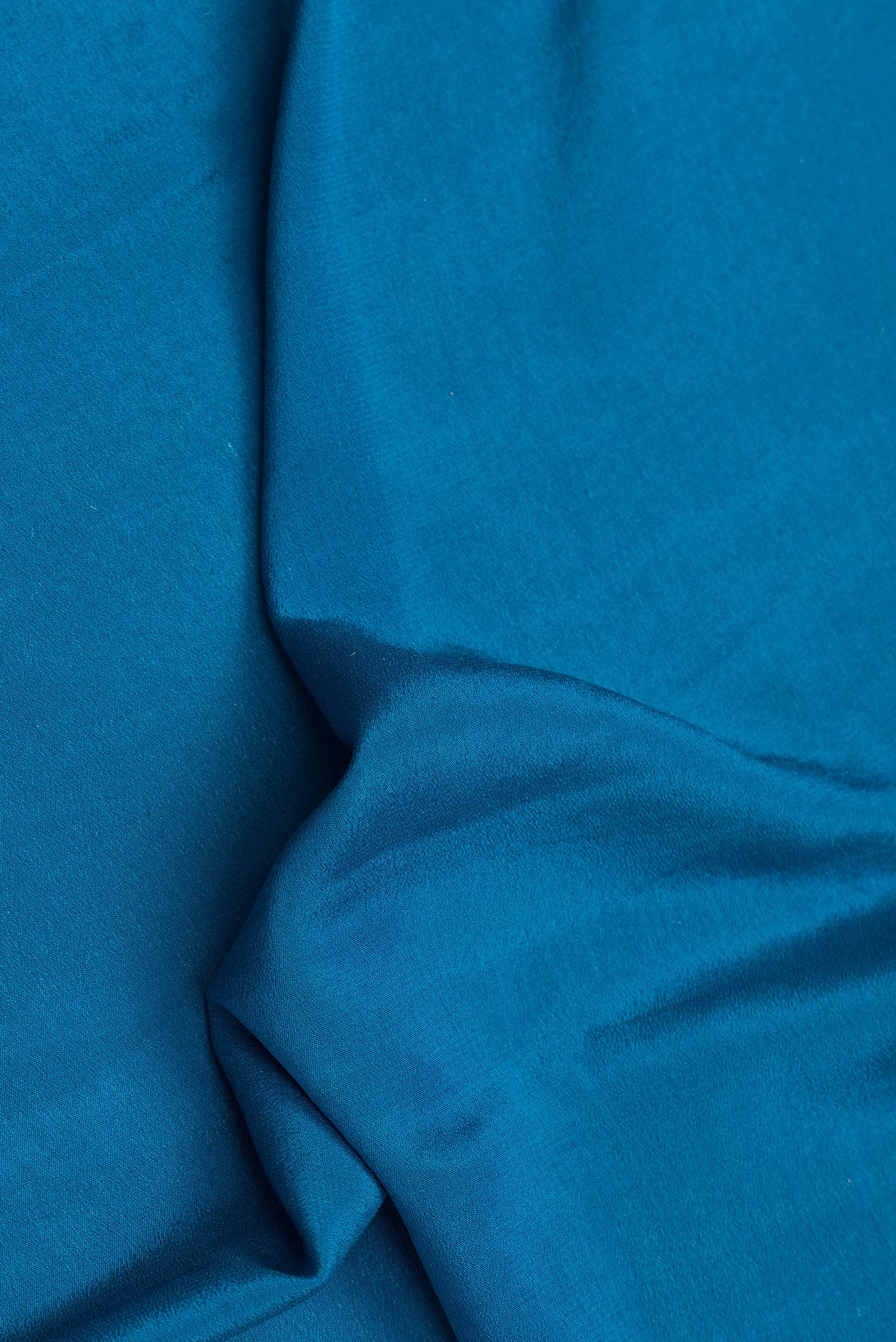 Close up of Peacock Blue Dual Tone Mysore Georgette Saree with Plain Body and Zari Border.  displaying folds