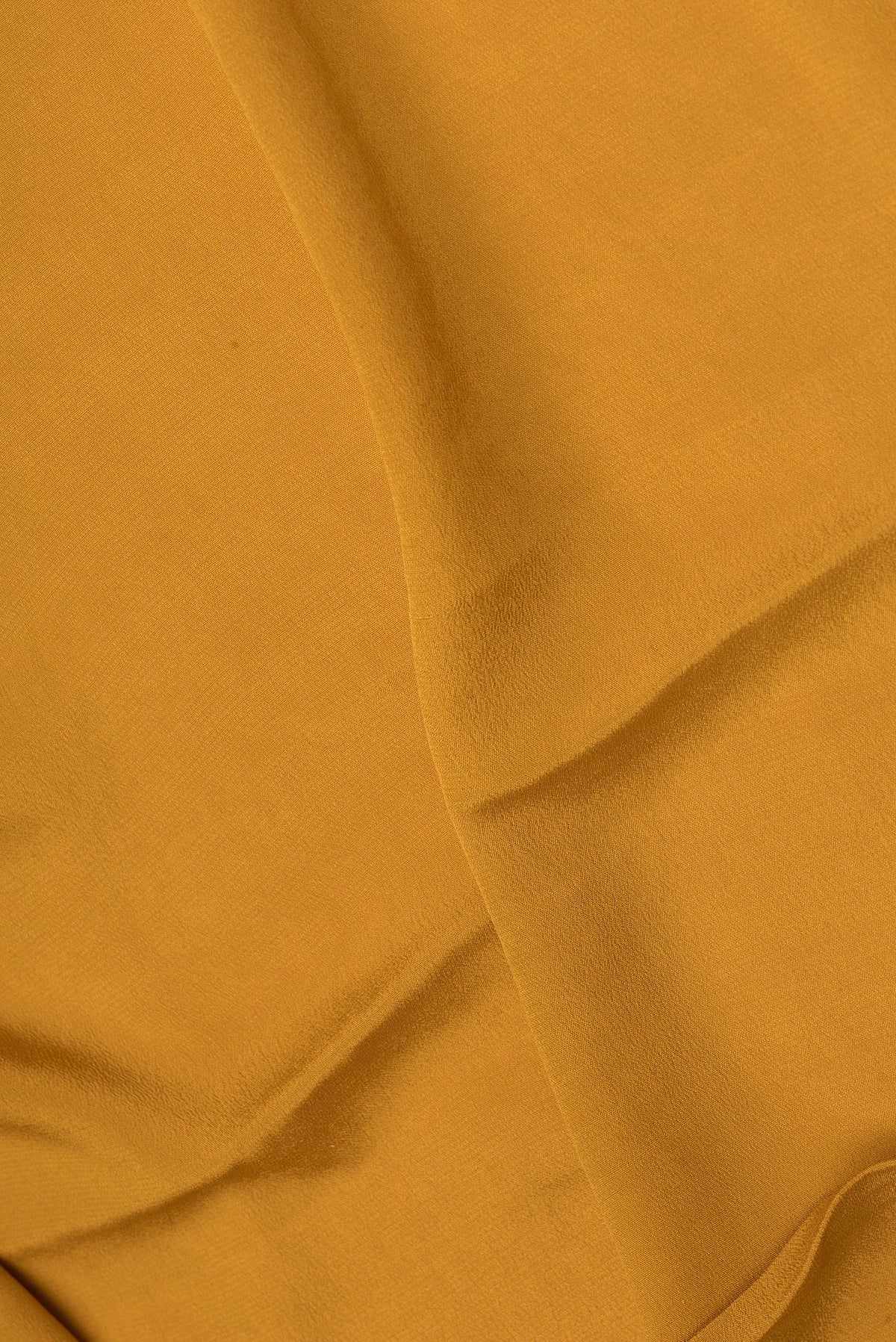Close up of Mustard Crepe Saree with Plain Body and Zari Border.  displaying folds