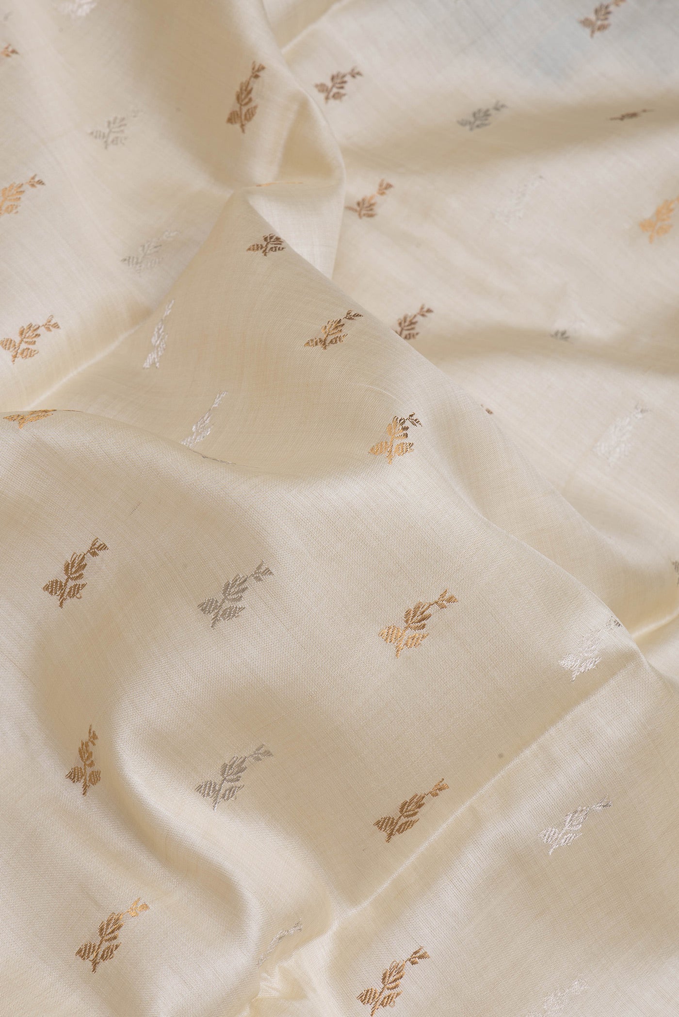 Close up of Off White Dual Tone Tussar Silk Saree with Zari Butta on the body and Without Border.  displaying folds