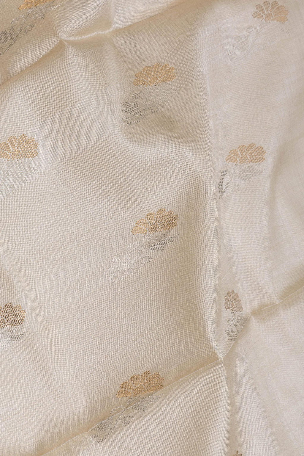 Close up of Beige Dual Tone Tussar Silk Saree with Zari Butta on the body and Without Border.  displaying folds