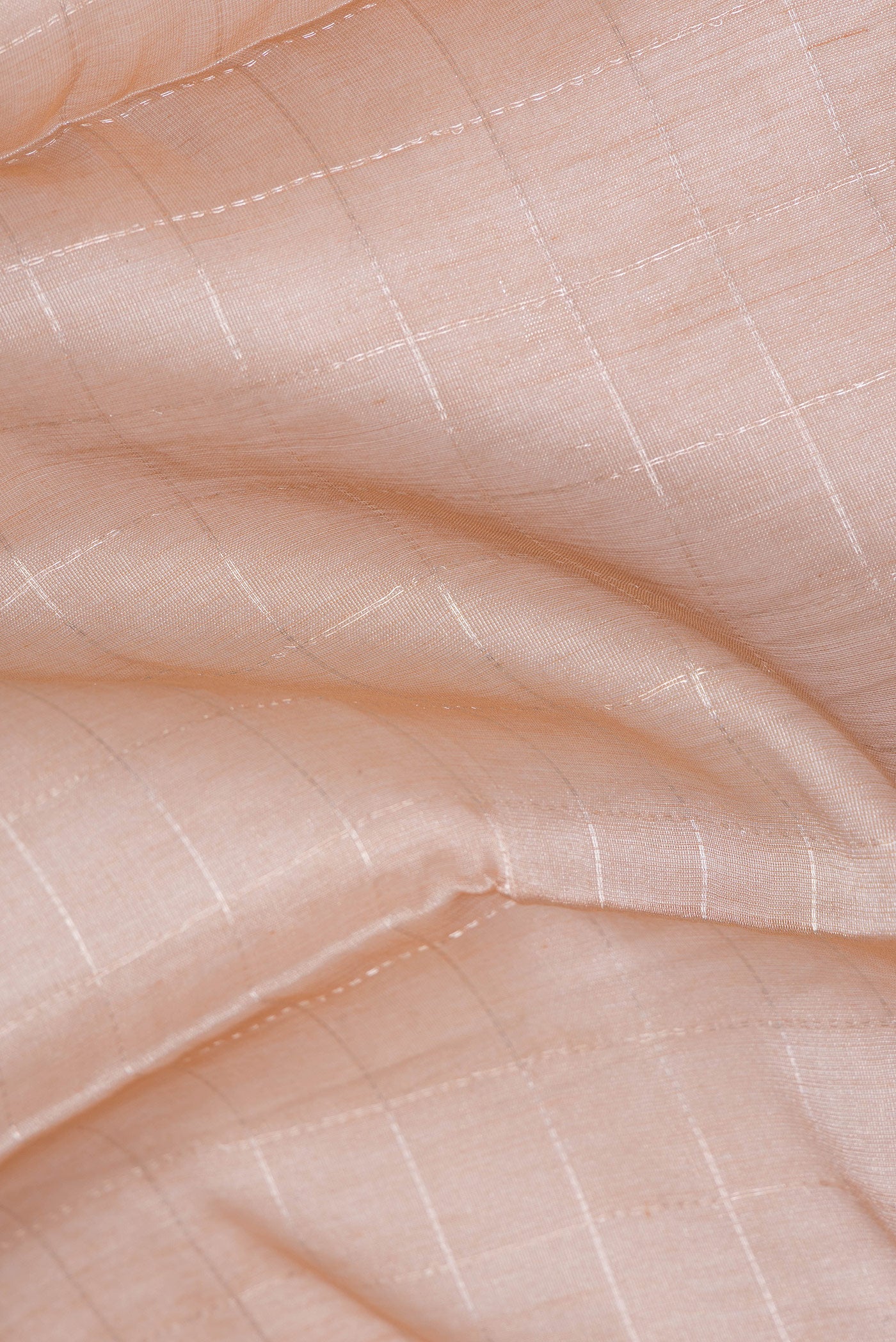 Close up of Peach Dual Tone Tussar Silk Saree with Checked design on the body and Zari Border.  displaying folds