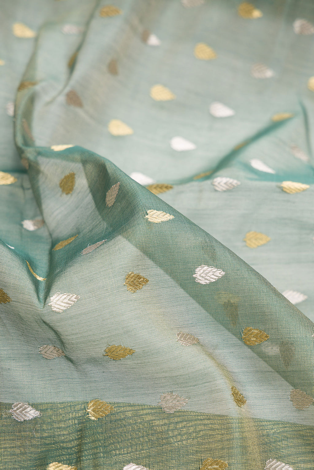 Close up of Green Dual Tone Chanderi Tissue Silk Saree with Zari Butta on the body and Zari Border.  displaying folds